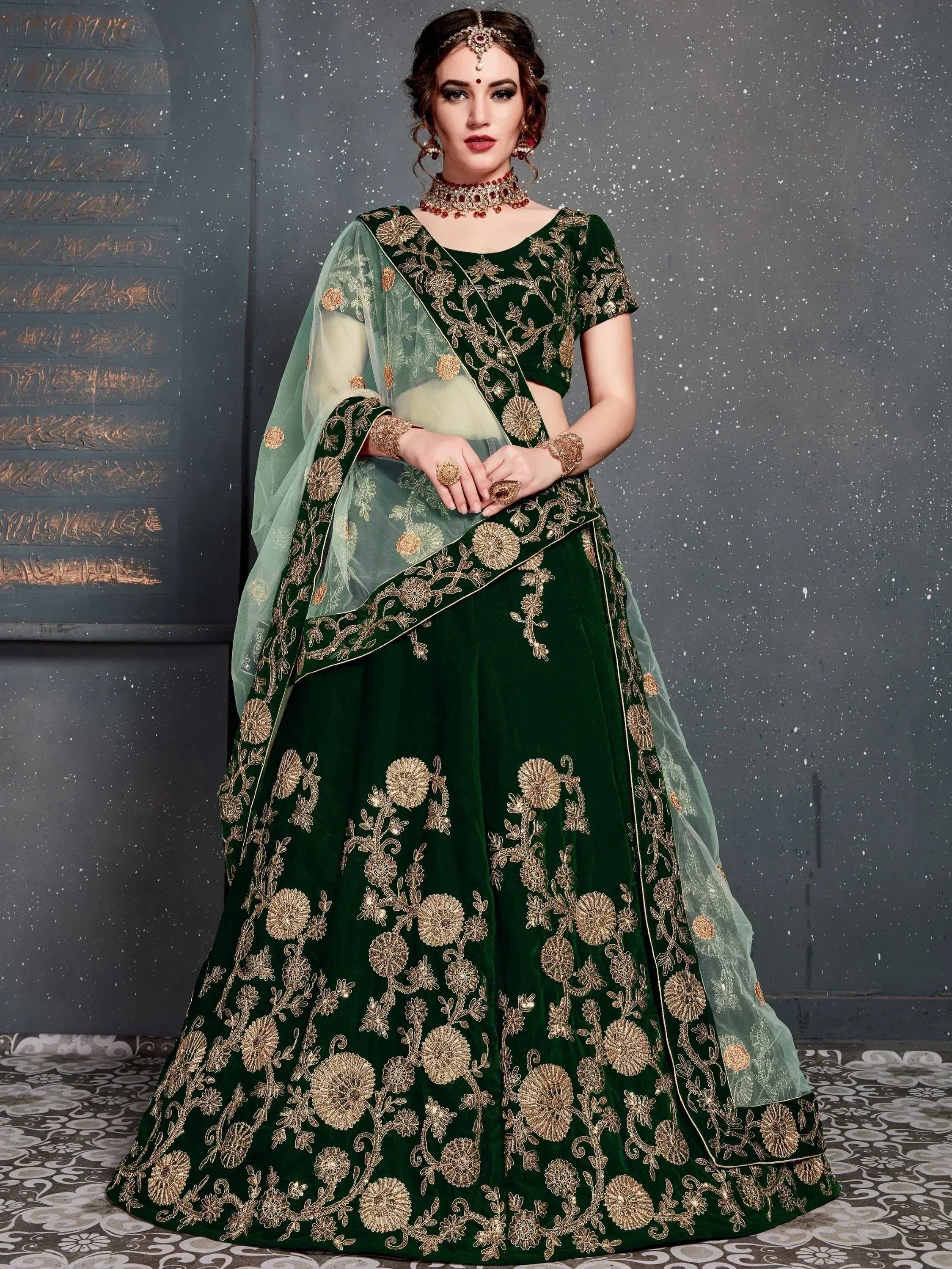 Emerald green velvet lehenga choli with gold floral embroidery and sheer dupatta, perfect for Indian weddings.