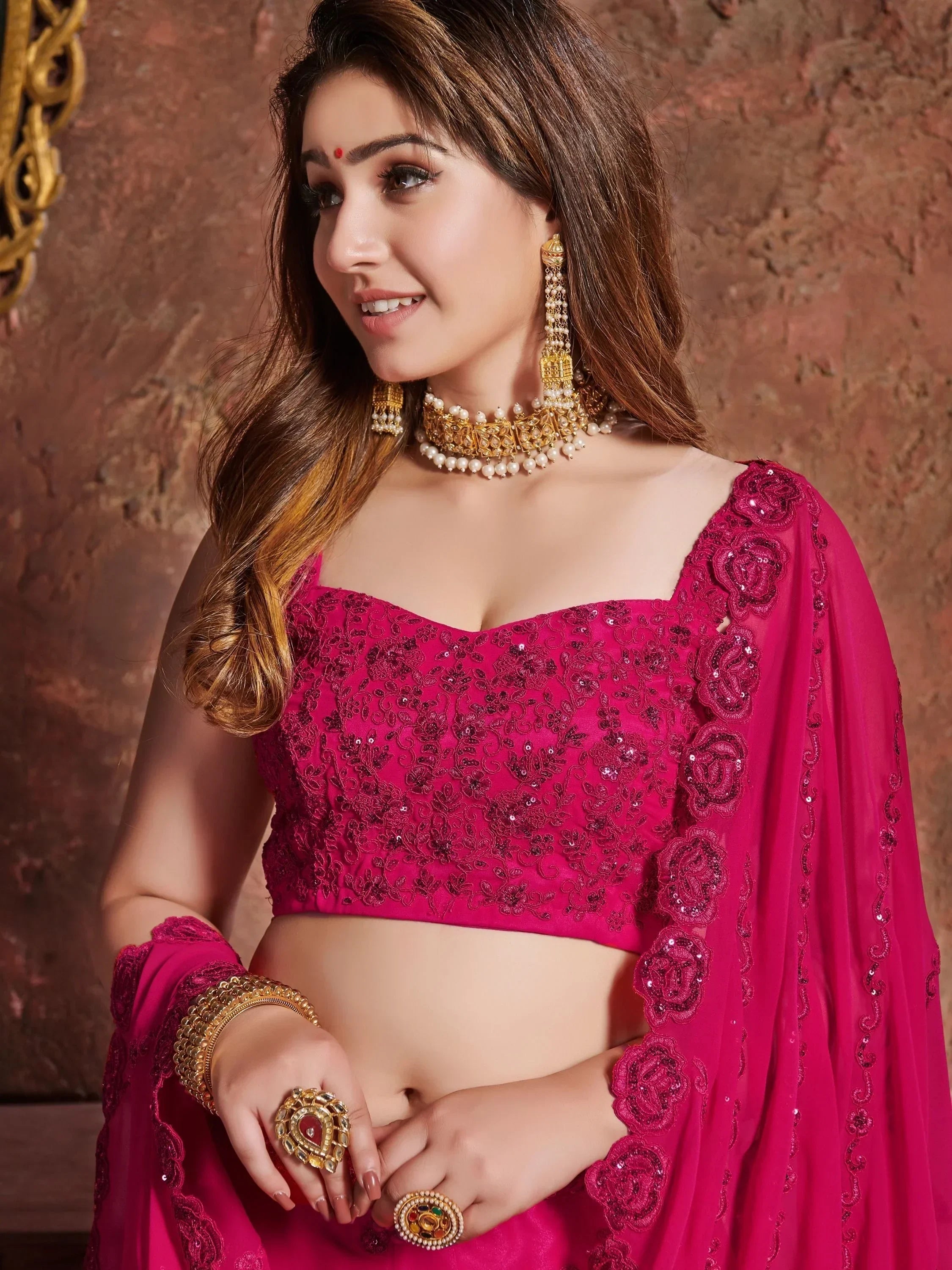 Pink embroidered lehenga choli with floral detailing, gold jewelry, and dupatta for Indian ethnic wear