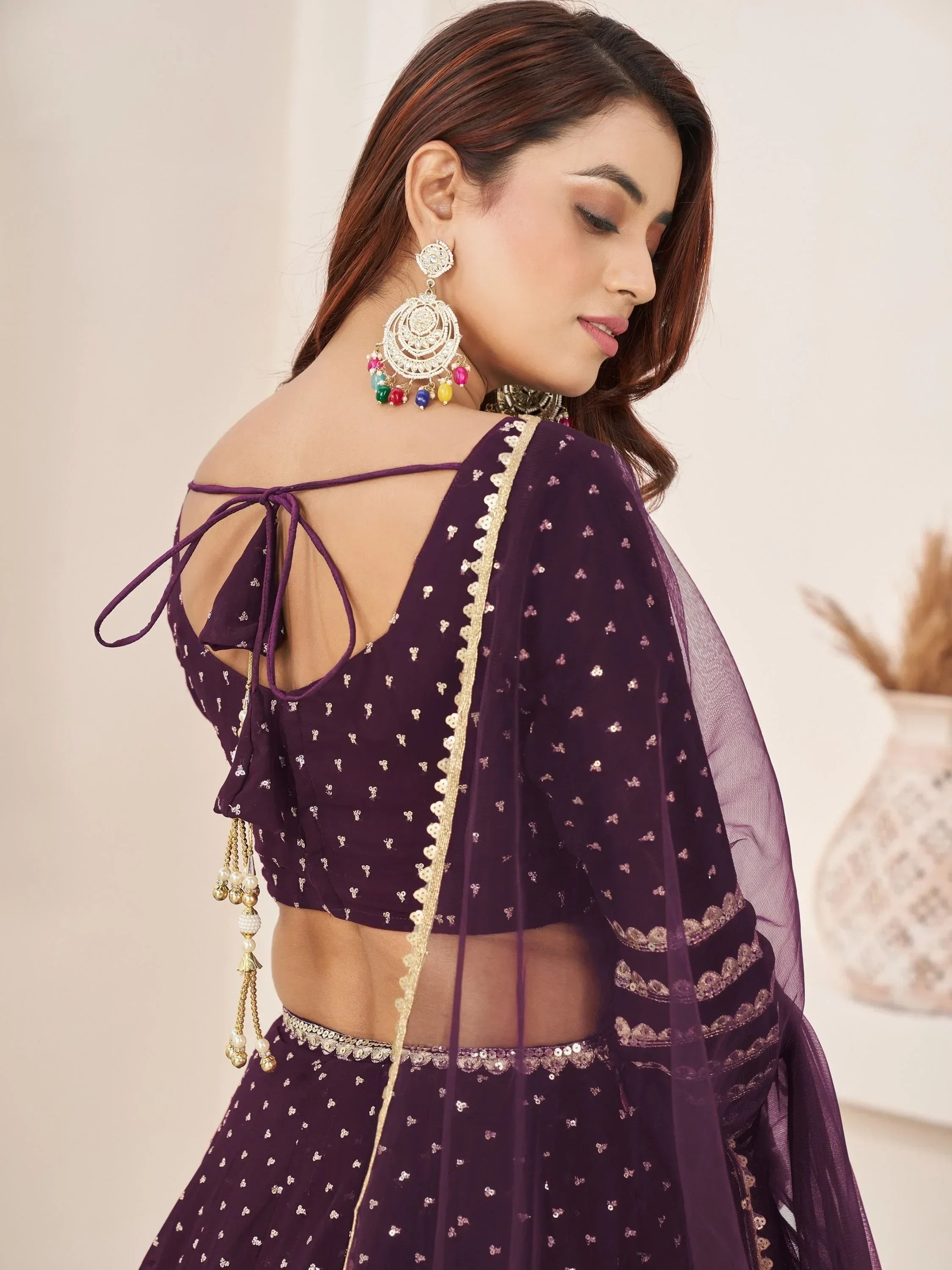 Purple ethnic lehenga choli with back tie-up, gold embroidery, and colorful jhumka earrings