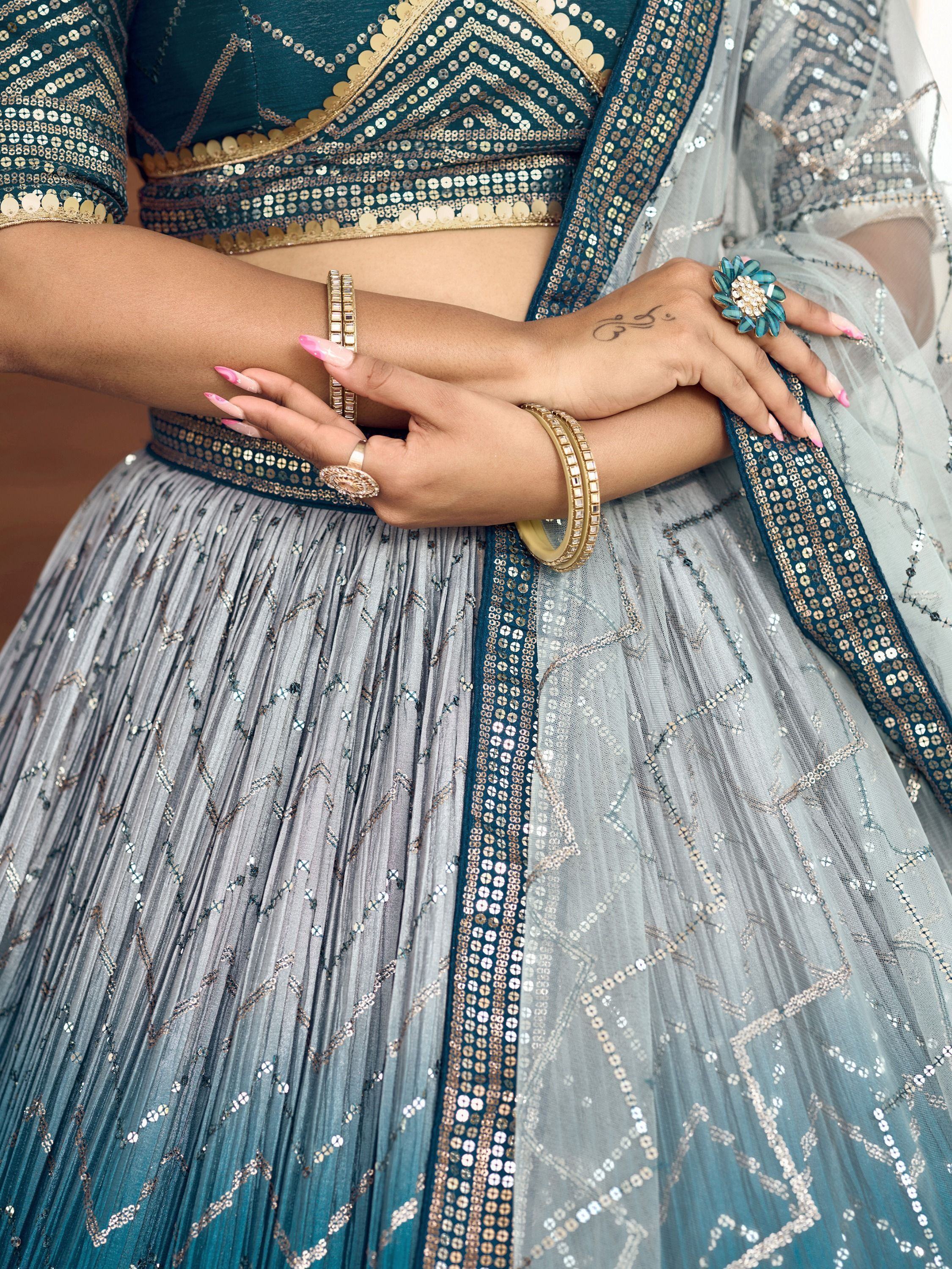 Teal and silver sequin lehenga choli with pleated skirt, gold bangles, and floral ring for Indian ethnic wear