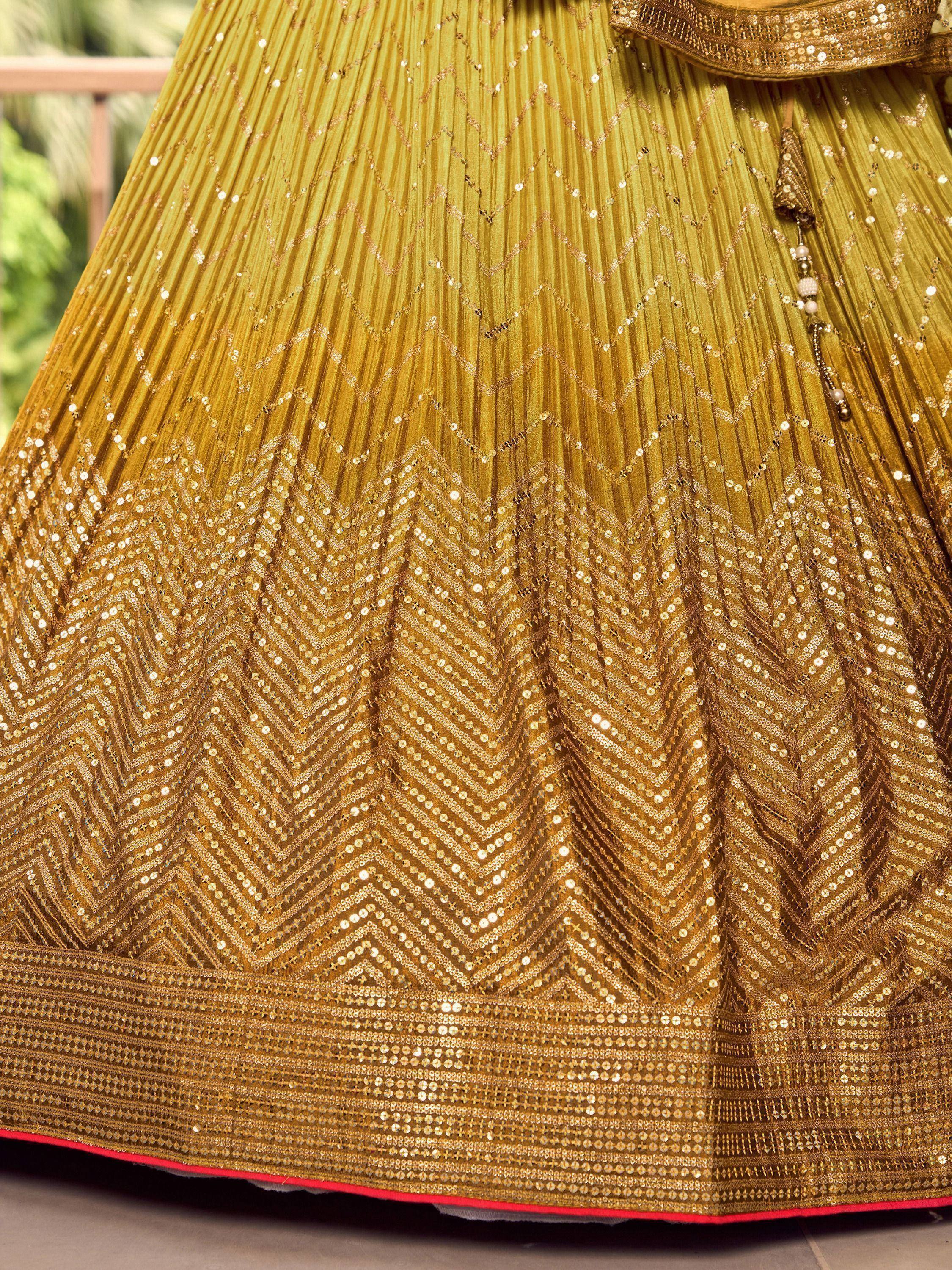 Golden pleated lehenga with sequin chevron patterns and tassel detail, ideal for Indian ethnic wear.