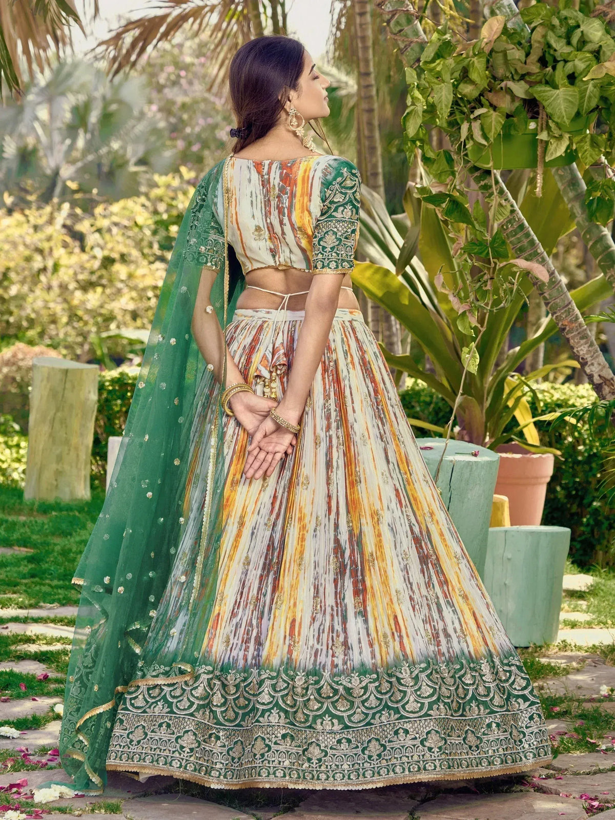 Woman in colorful printed lehenga choli with green dupatta, ethnic Indian wear for weddings or festivals