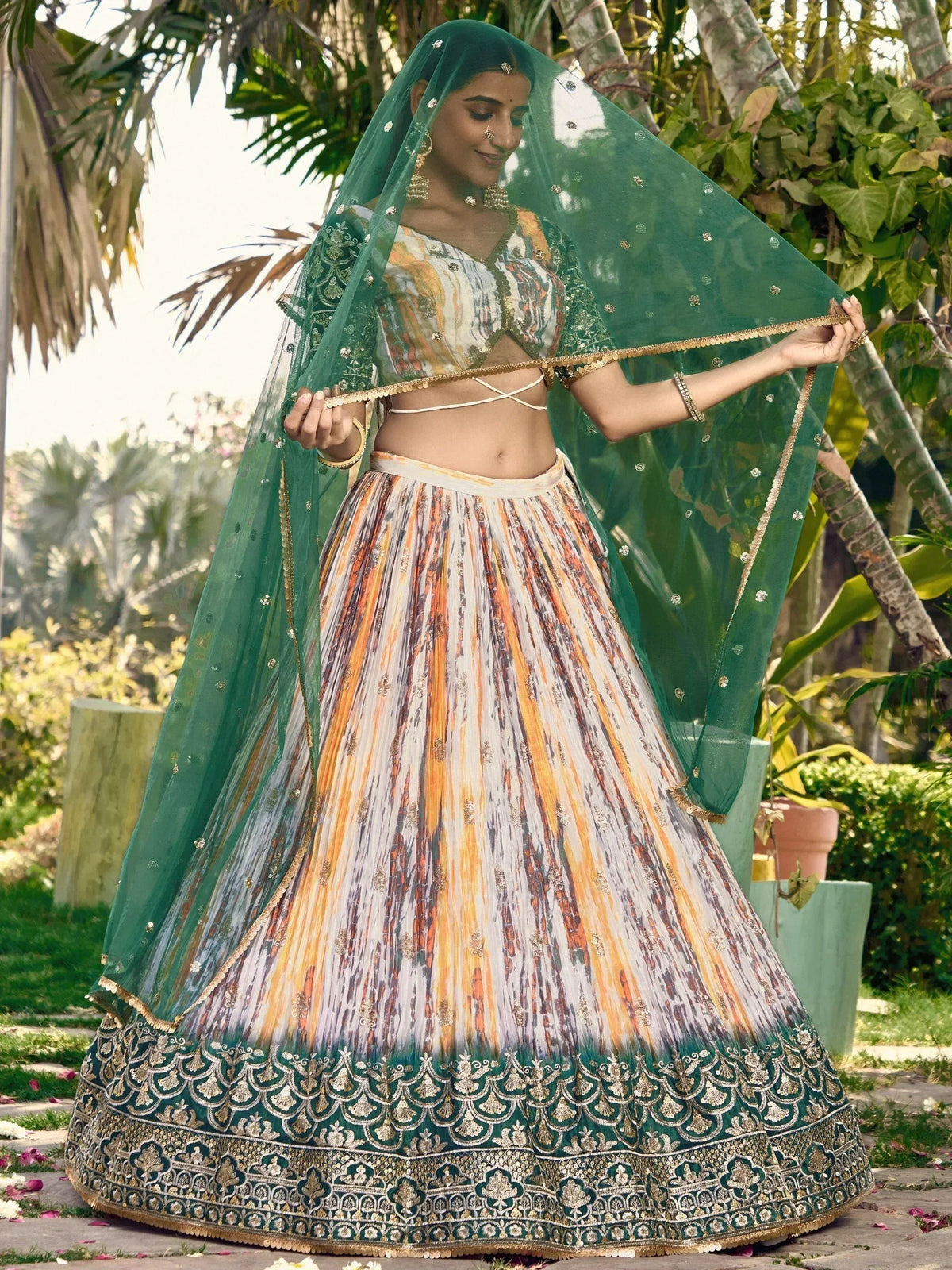 Woman in designer lehenga choli with green dupatta, floral print skirt, and gold embroidery, perfect for Indian ethnic occasions.