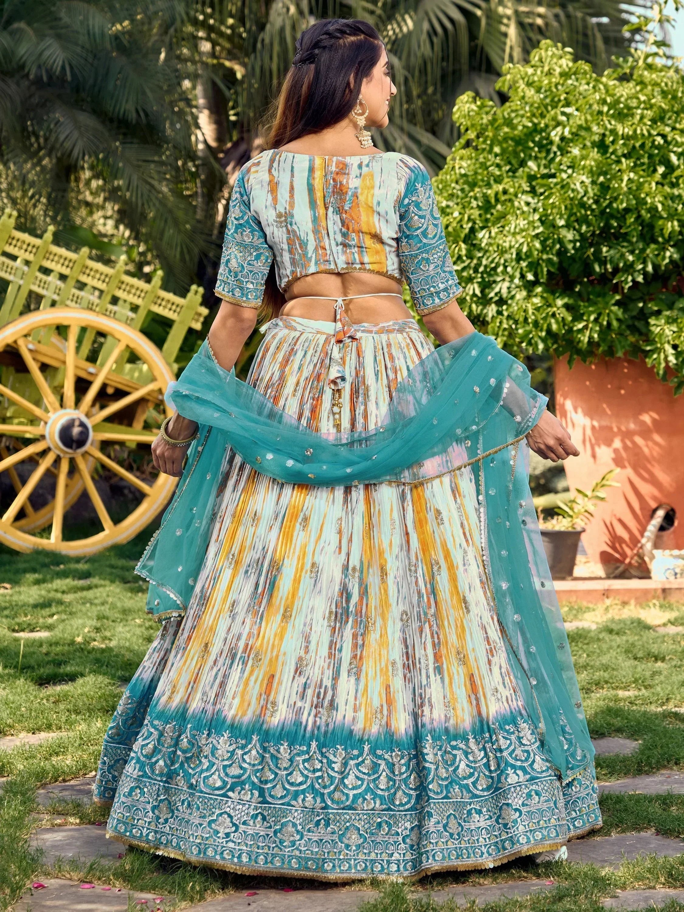 Woman in colorful printed lehenga choli with embroidered dupatta, garden setting