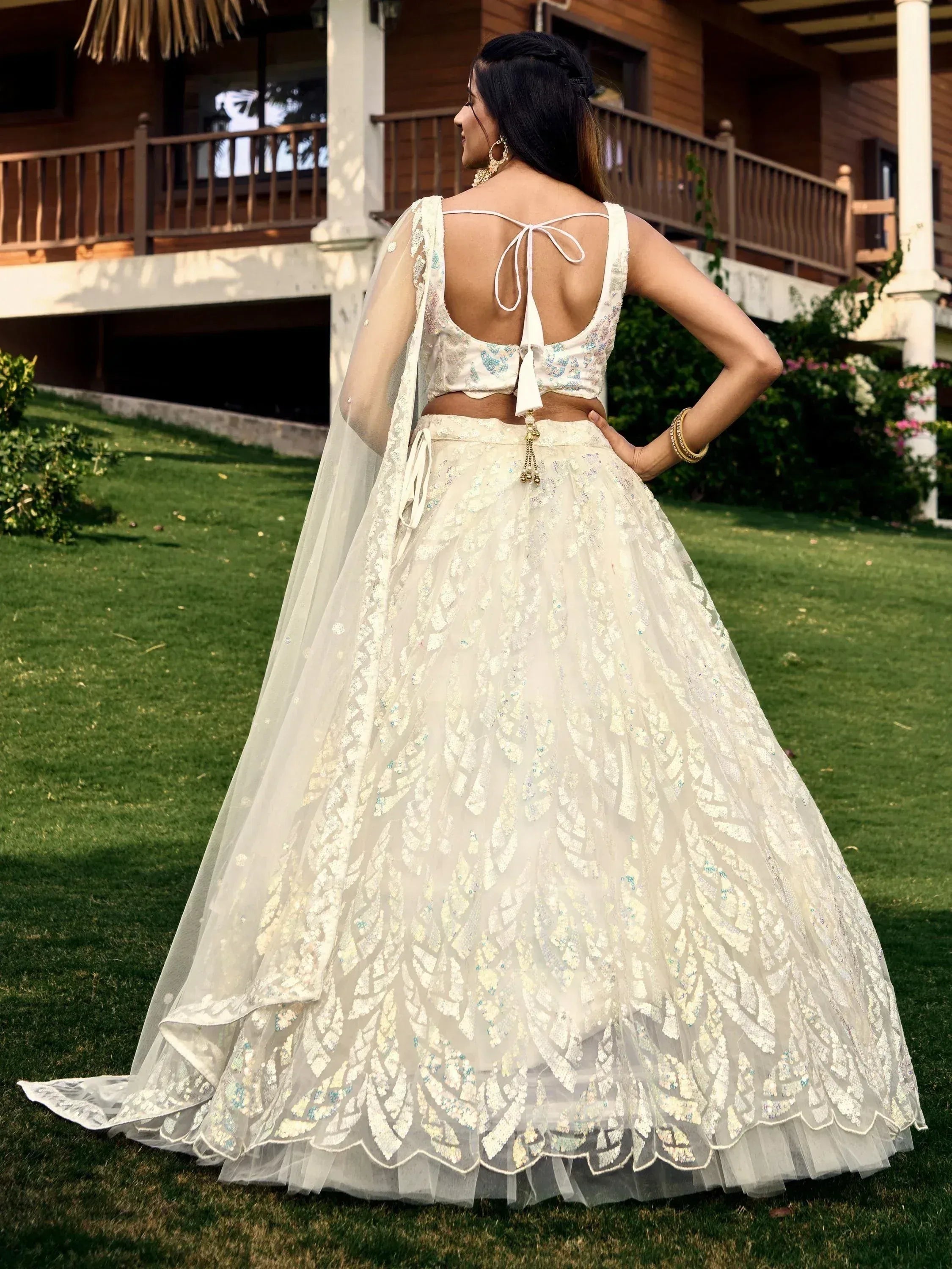Elegant white lehenga choli with floral embroidery, back tie blouse, and sheer dupatta, perfect for Indian weddings or festive occasions.