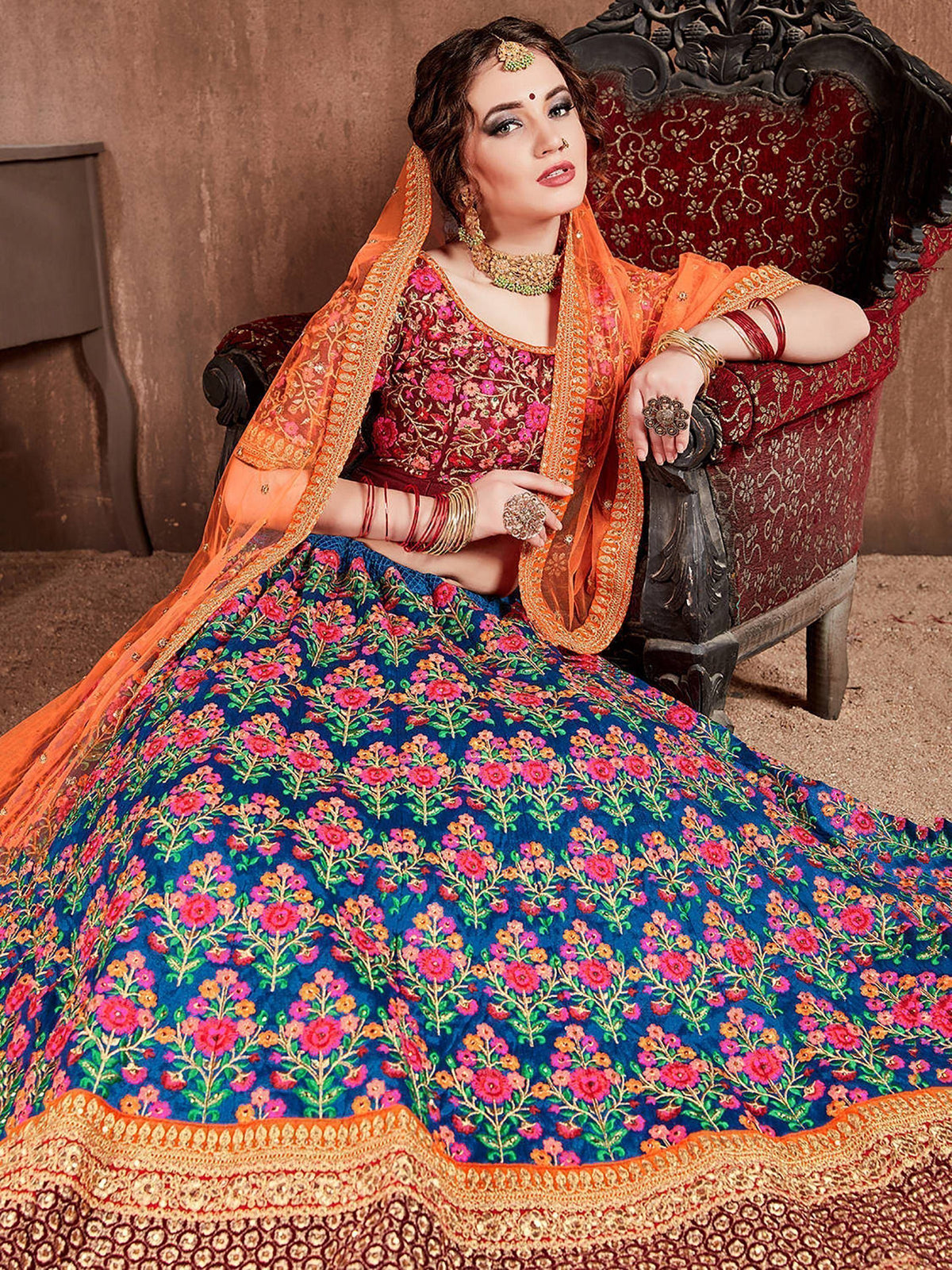 Woman in vibrant floral lehenga choli with orange dupatta, traditional Indian ethnic wear for weddings and festivals