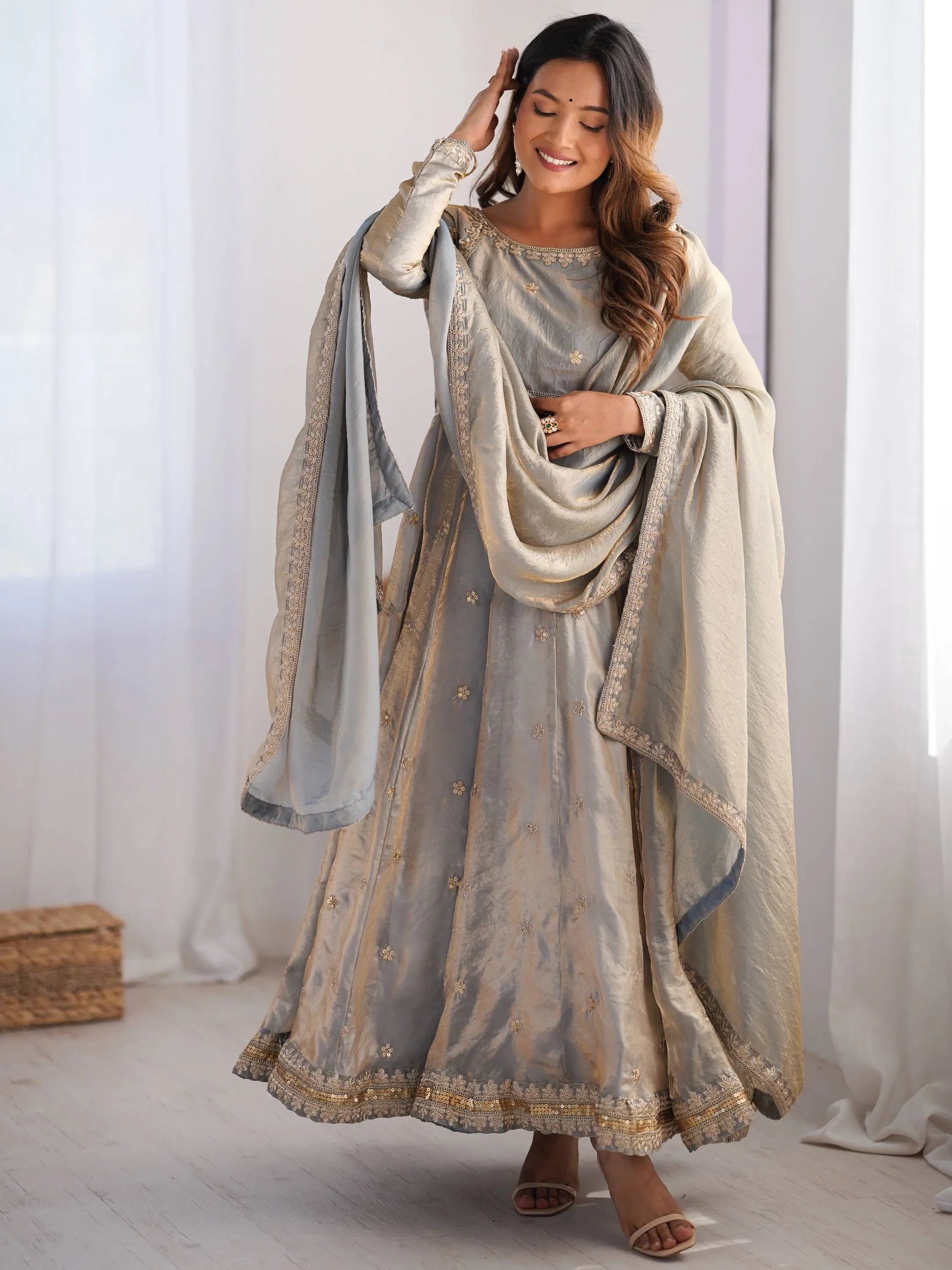 Woman wearing a grey ethnic engagement gown with golden embroidery and dupatta indoors