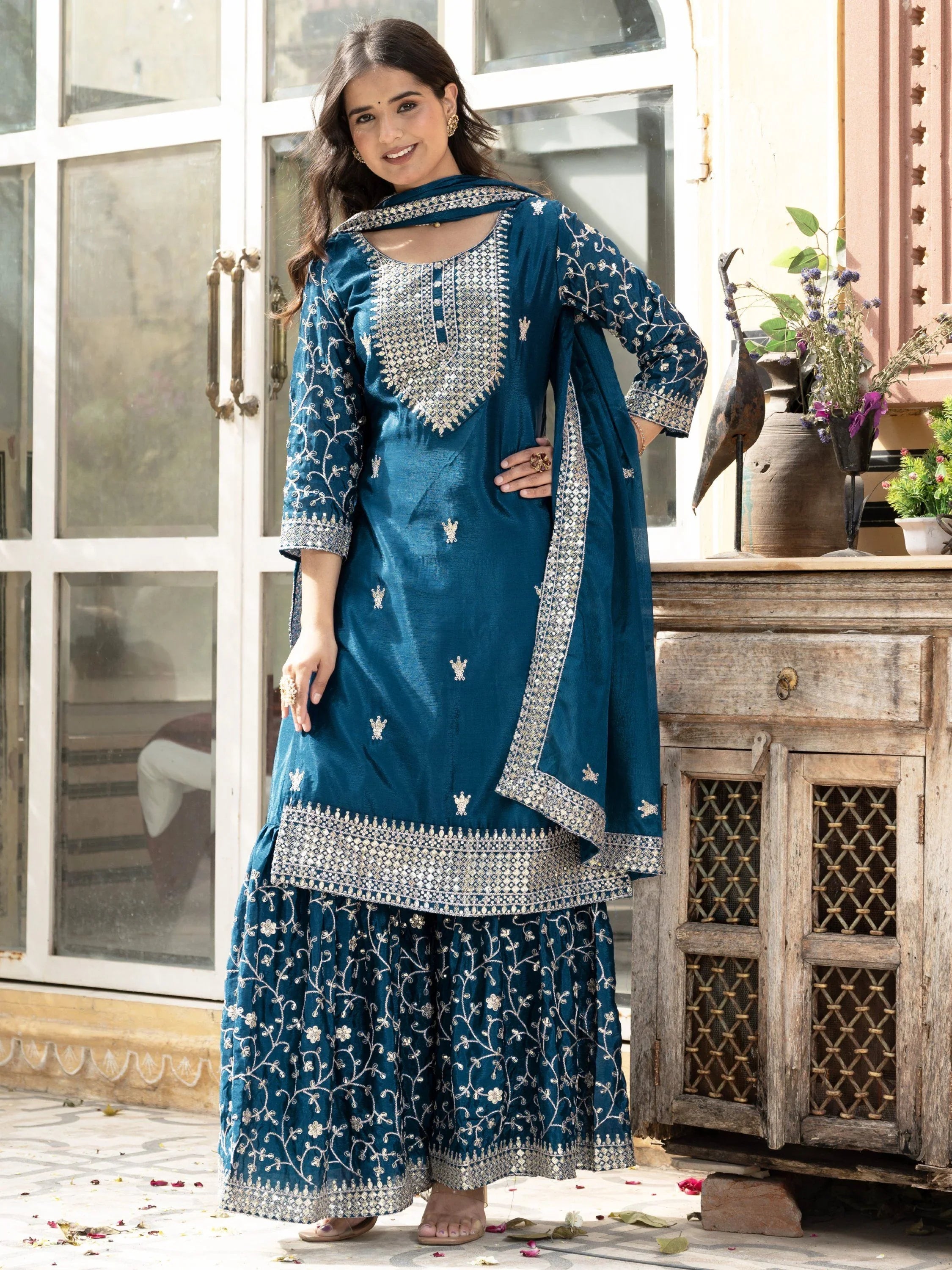 Woman wearing blue hand embroidered sharara suit with dupatta, floral and mirror work design