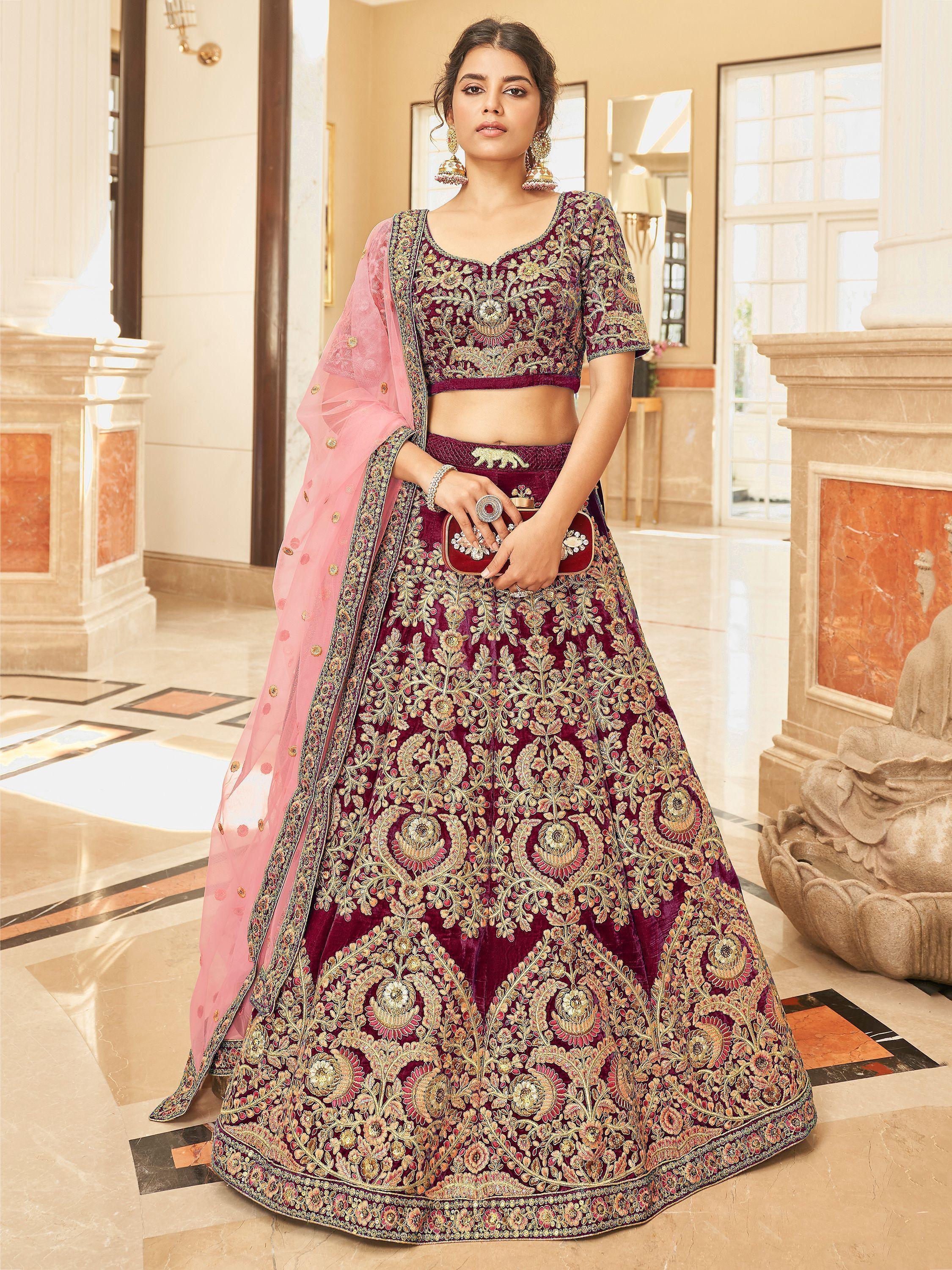 Woman wearing maroon Lakhnavi embroidered bridal lehenga choli with pink dupatta indoors