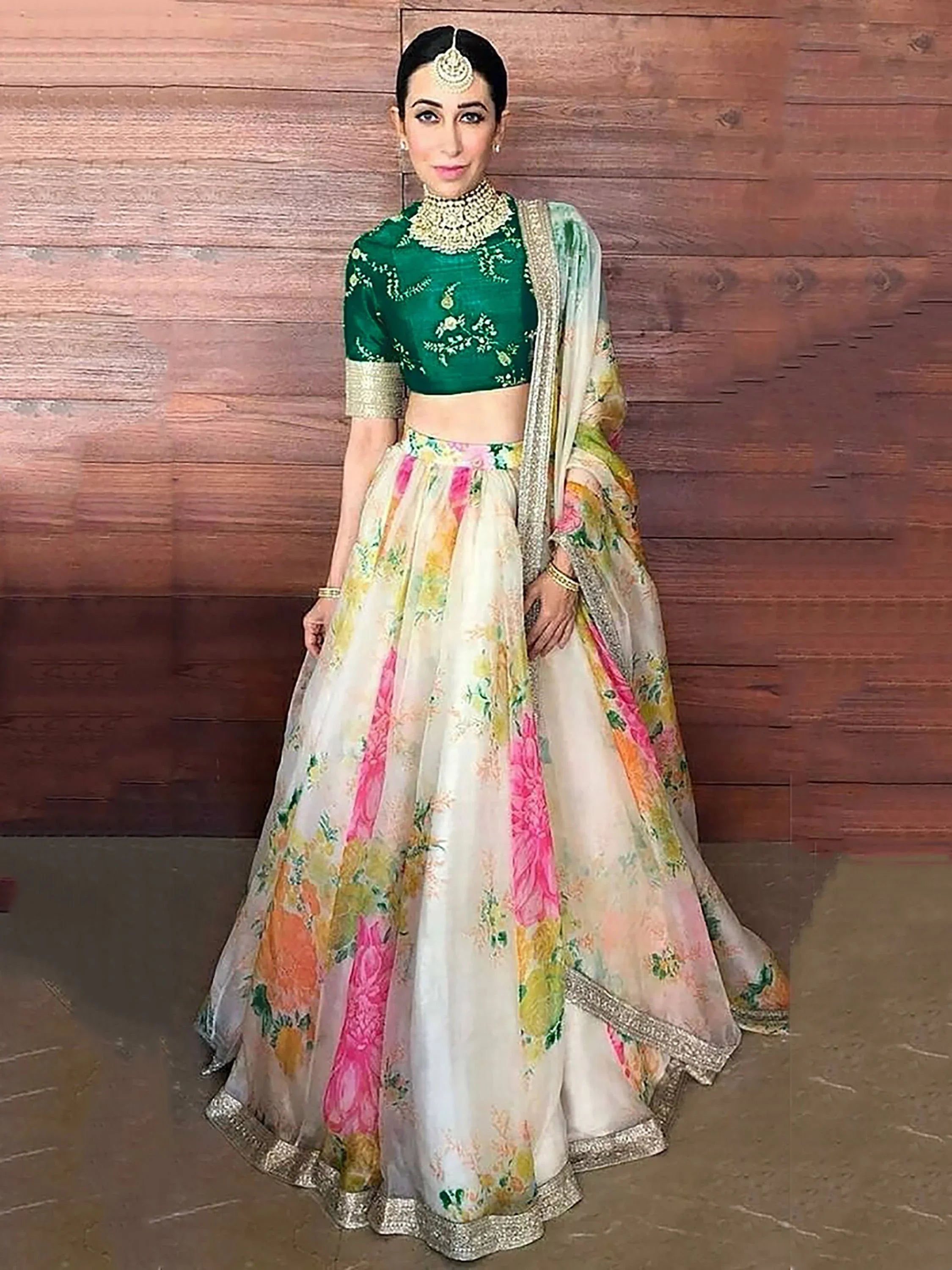 Woman wearing green floral embroidered blouse and organza lehenga choli with dupatta