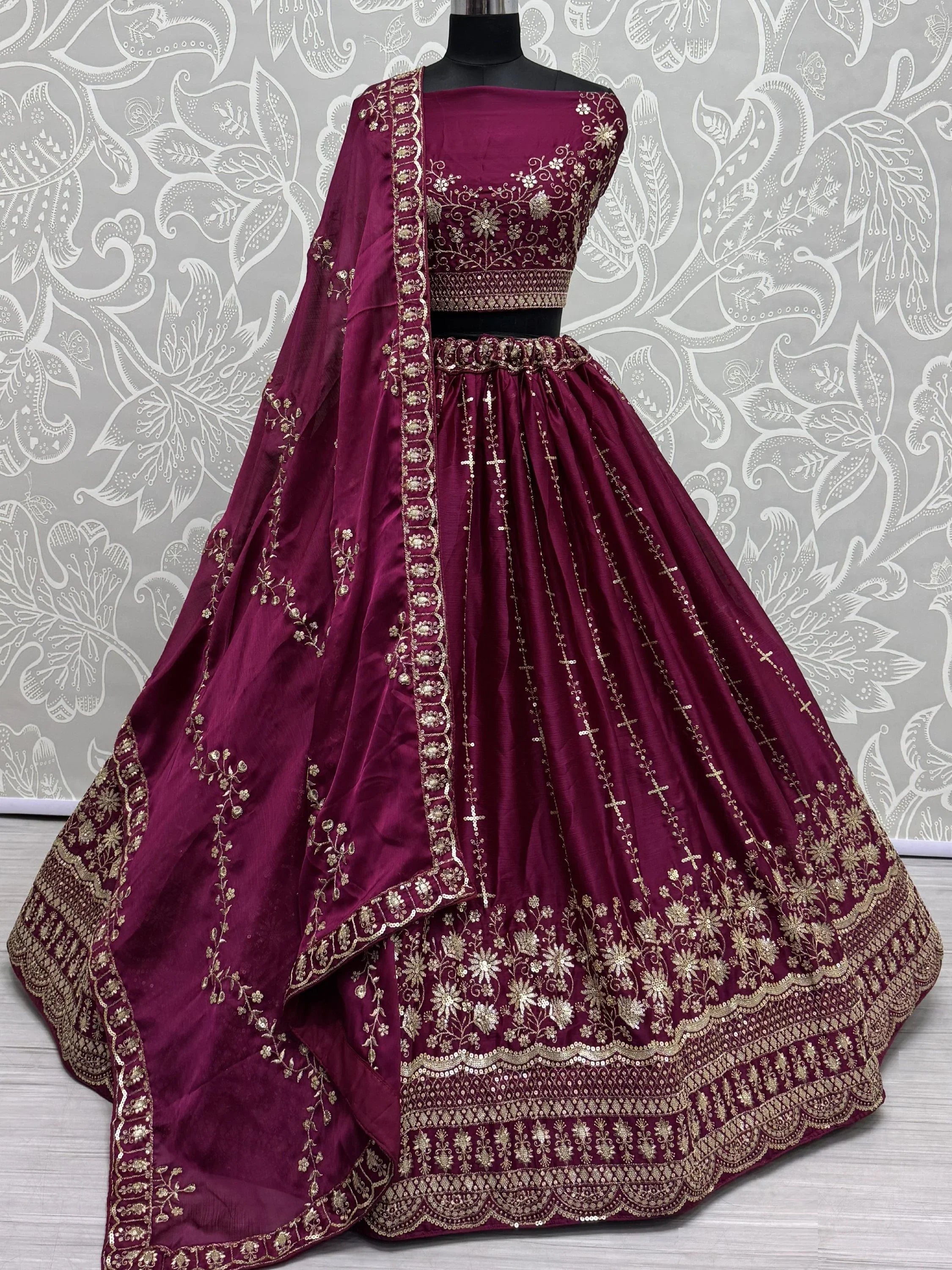 Maroon satin bridal lehenga choli with gold embroidery and matching dupatta on mannequin
