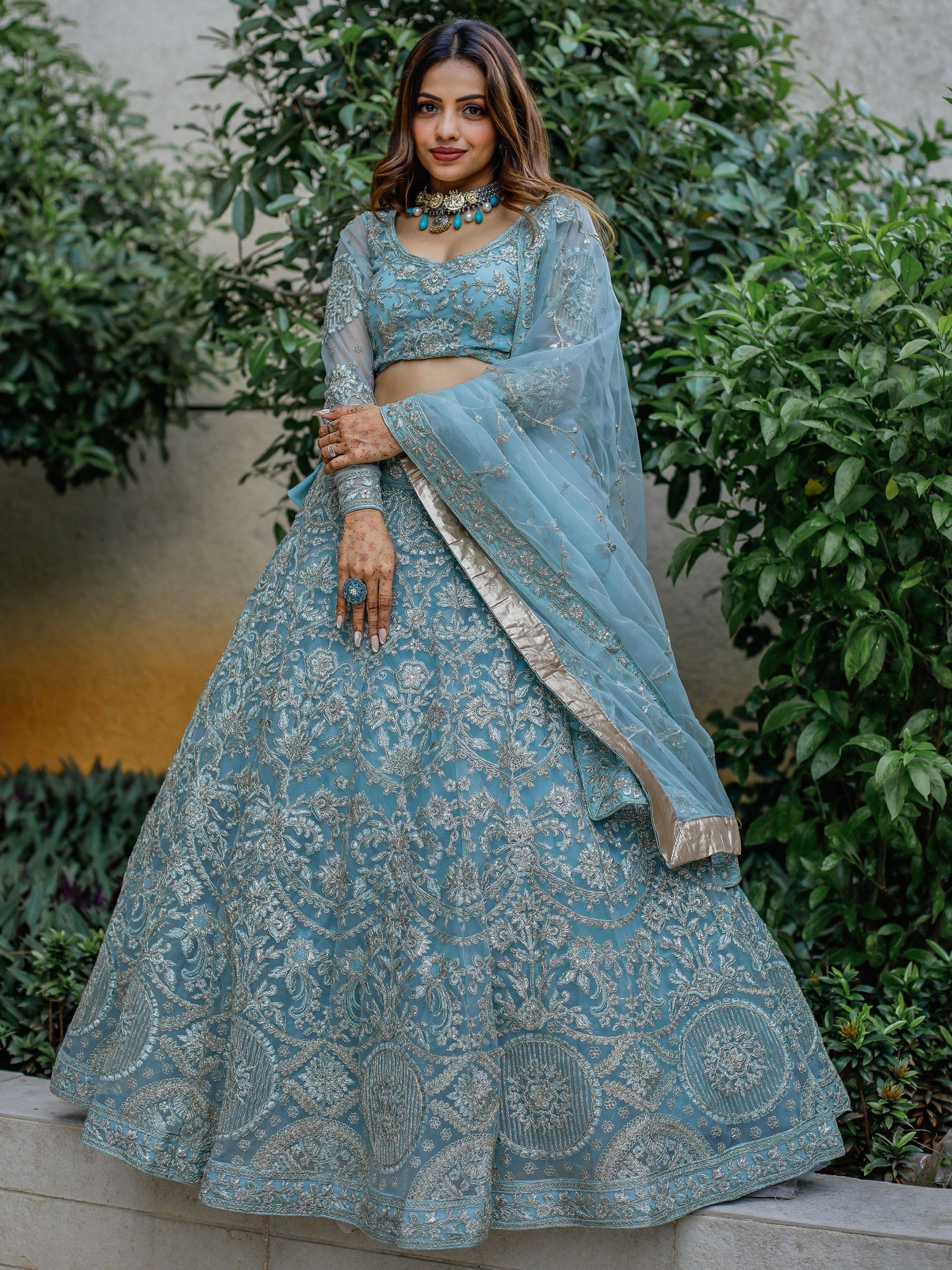 Woman in a sky blue bridal lehenga choli with silver embroidery and dupatta, outdoor setting