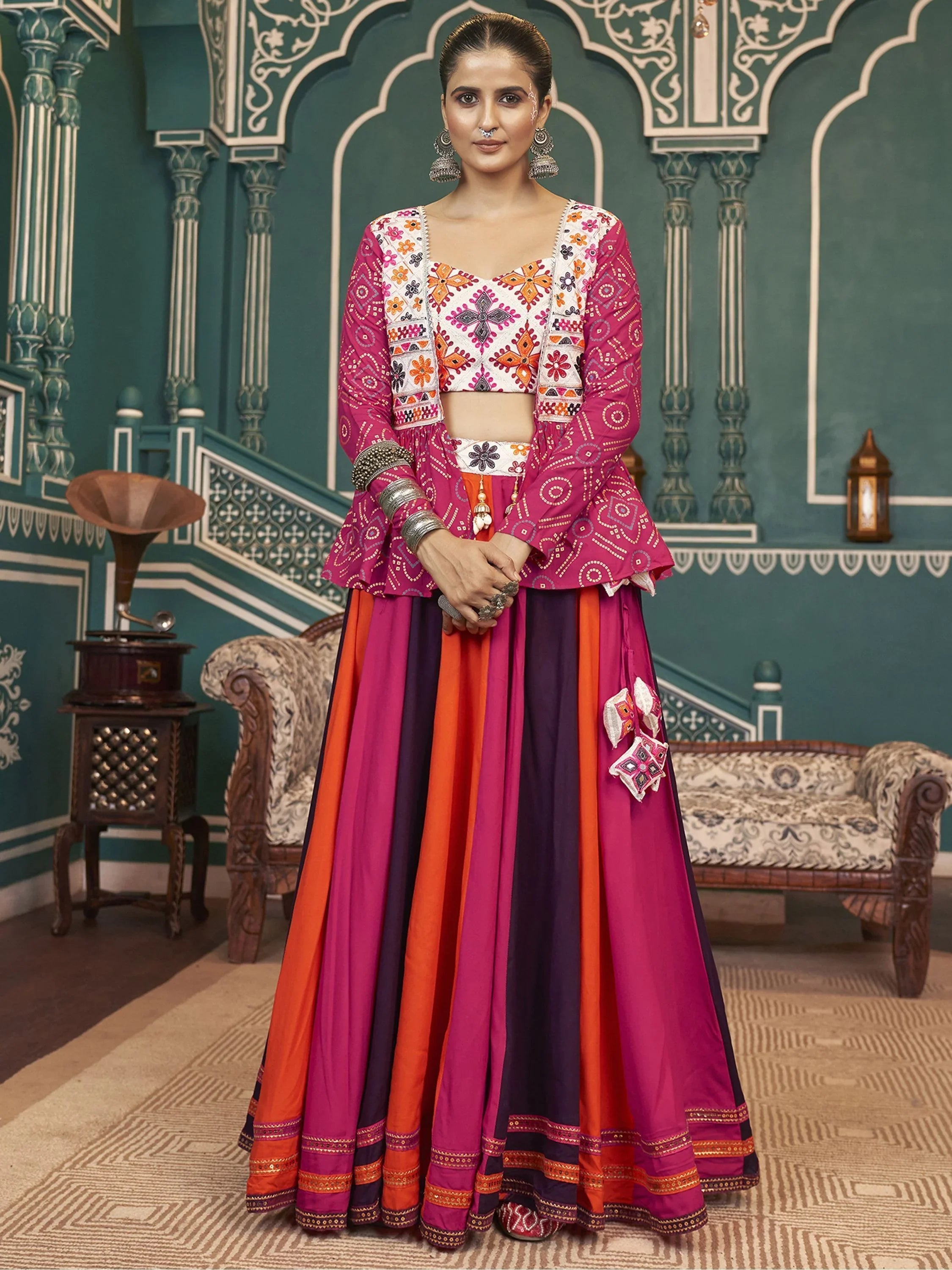 Woman wearing vibrant pink and orange taffeta Navratri lehenga choli with mirror work