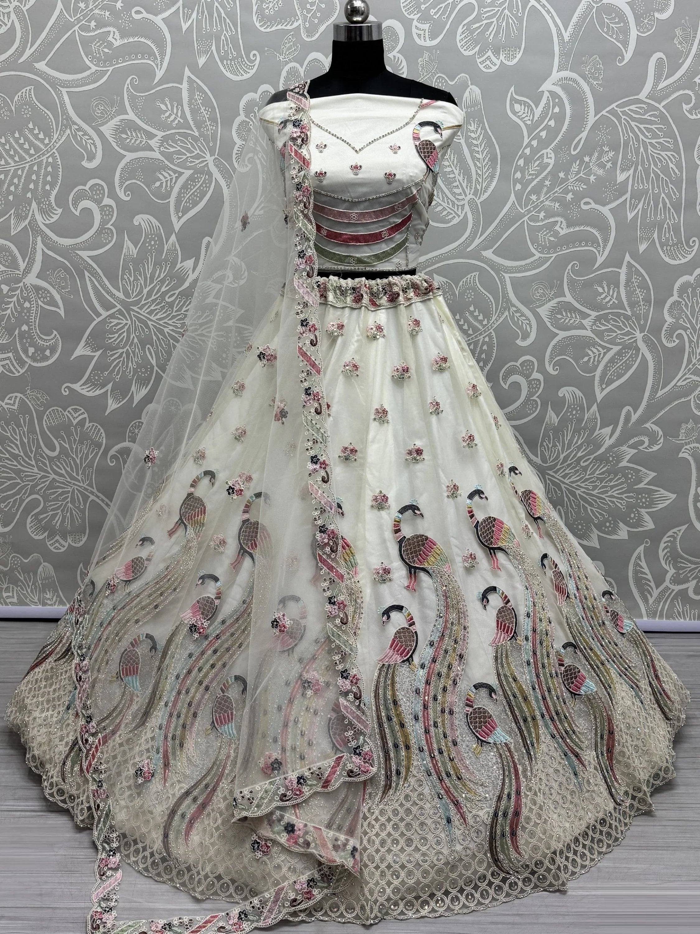 White bridal lehenga choli with pink peacock embroidery and net dupatta on mannequin