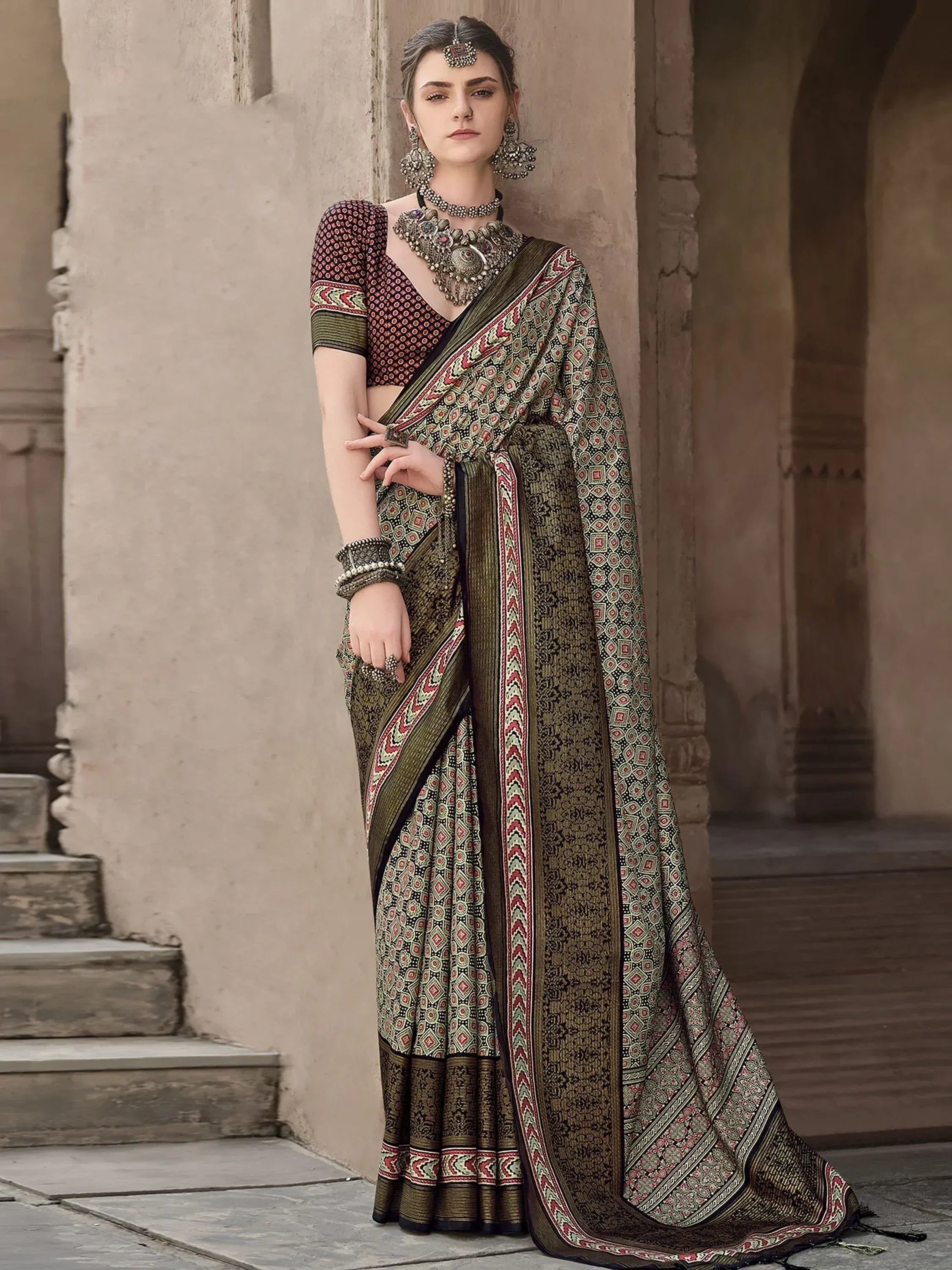 Woman in elegant Indian saree with intricate geometric print, traditional jewelry, and ethnic blouse, styled for festive occasions.