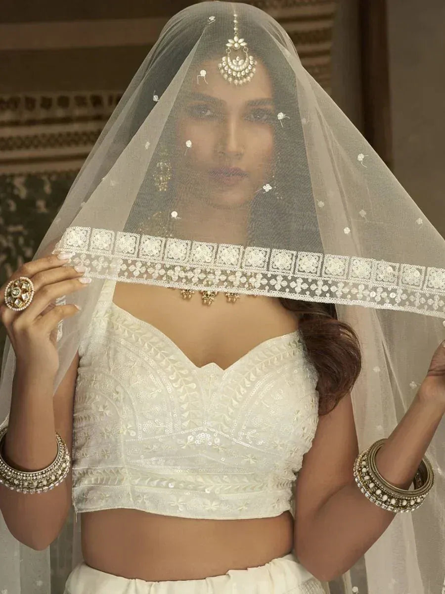 White embroidered lehenga choli with sheer veil and traditional jewelry for Indian bridal wear