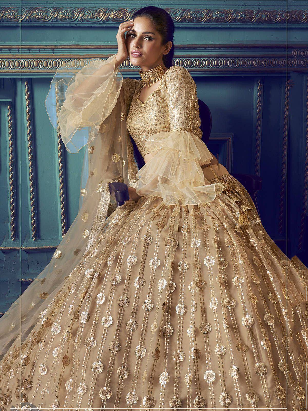 Elegant gold lehenga choli with sequin embroidery and sheer sleeves, perfect for Indian weddings and festive occasions.