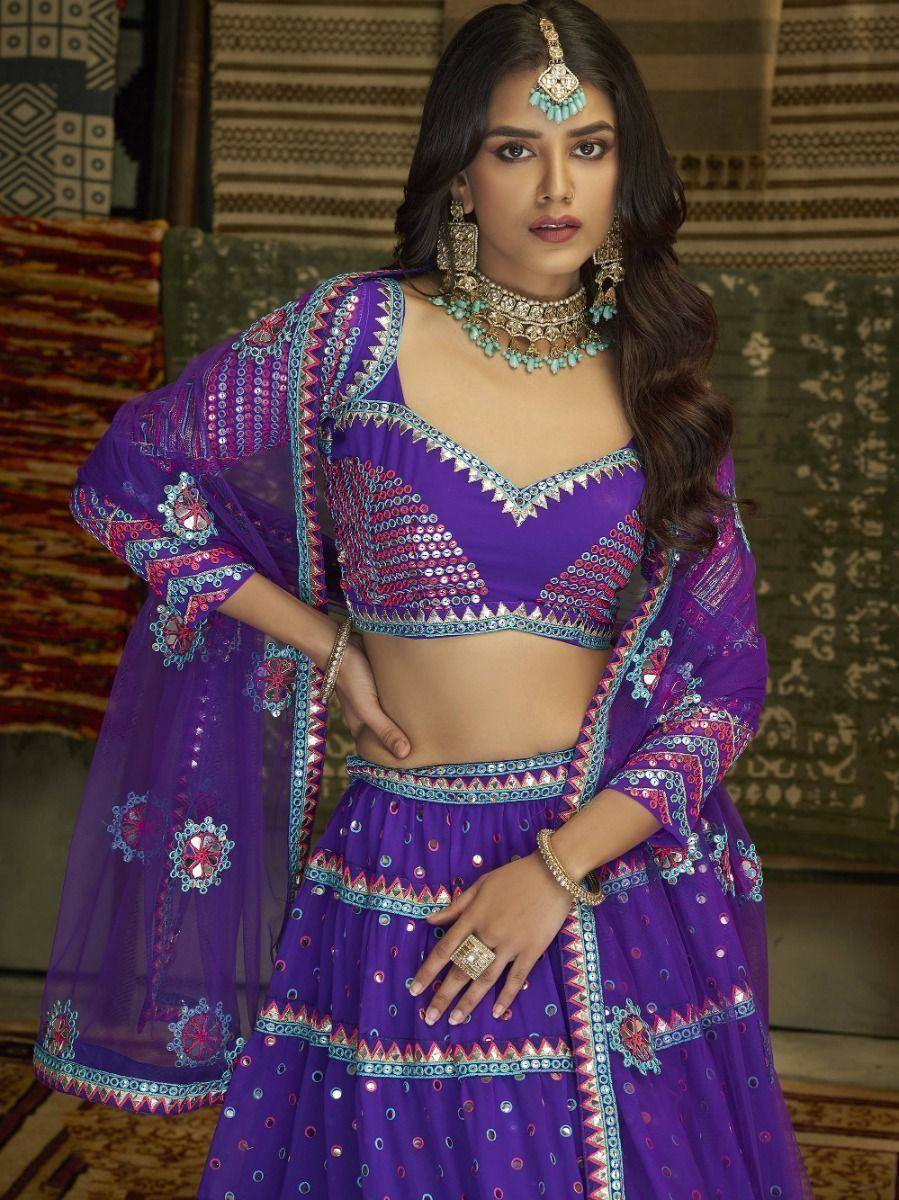 Purple embroidered lehenga choli with mirror work and dupatta, styled with traditional jewelry for ethnic occasions