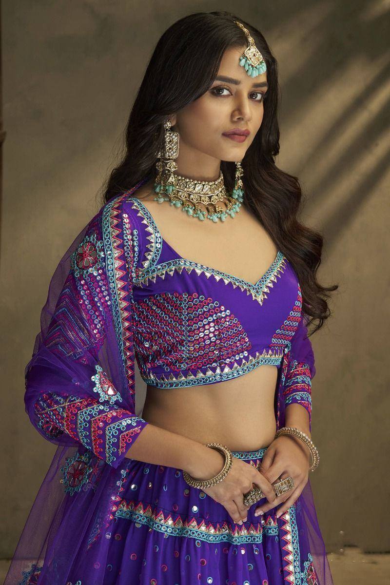 Purple embroidered lehenga choli with mirror work, paired with turquoise jewelry for Indian ethnic wear