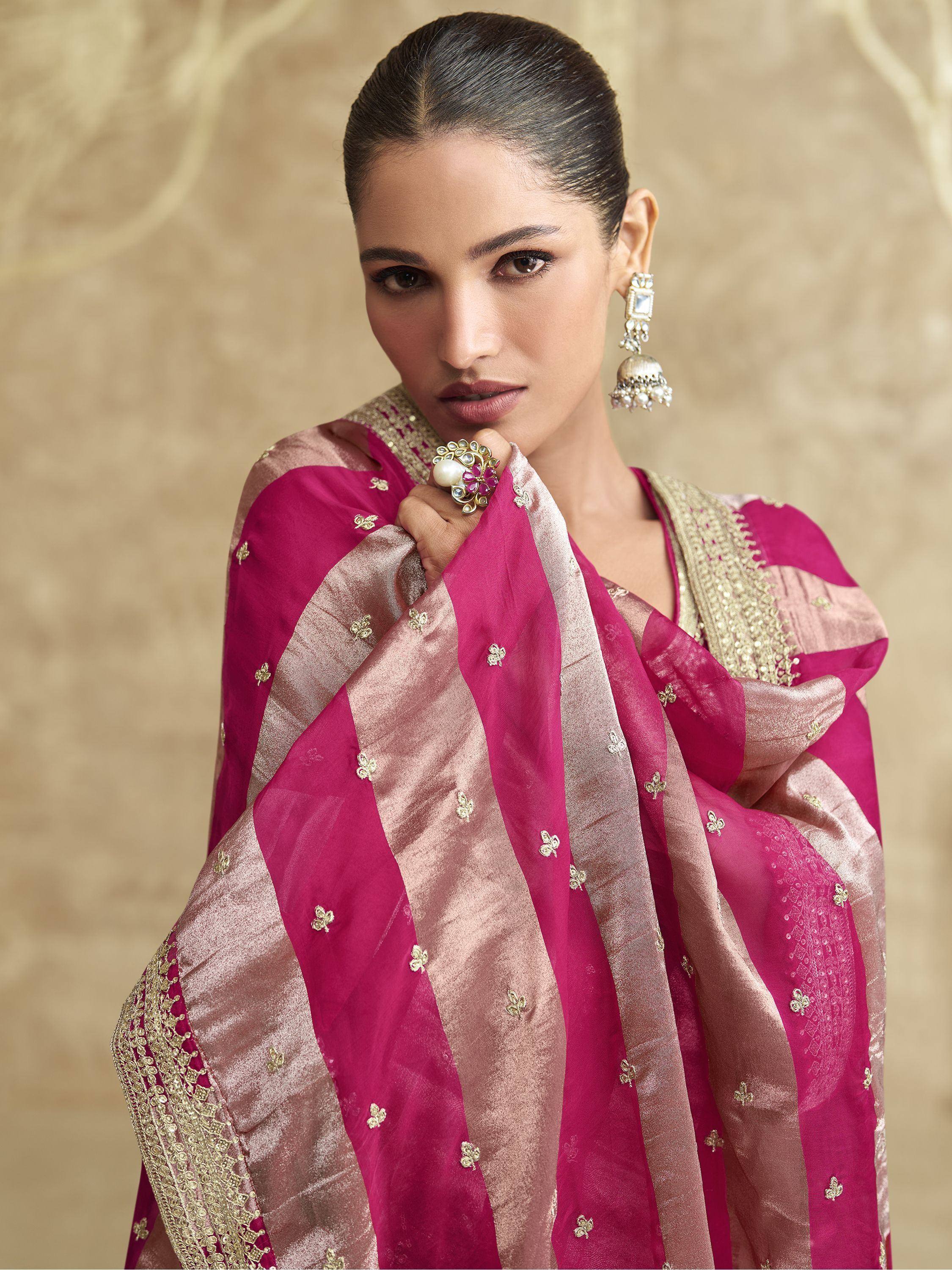 Elegant pink and gold embroidered saree with traditional Indian jewelry