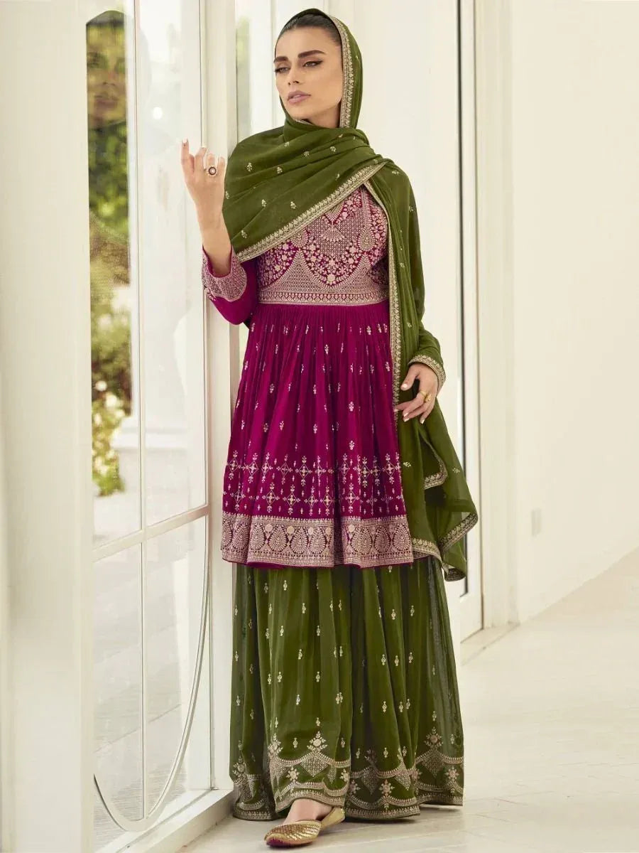 Woman in a maroon and olive green embroidered salwar kameez with dupatta, standing indoors