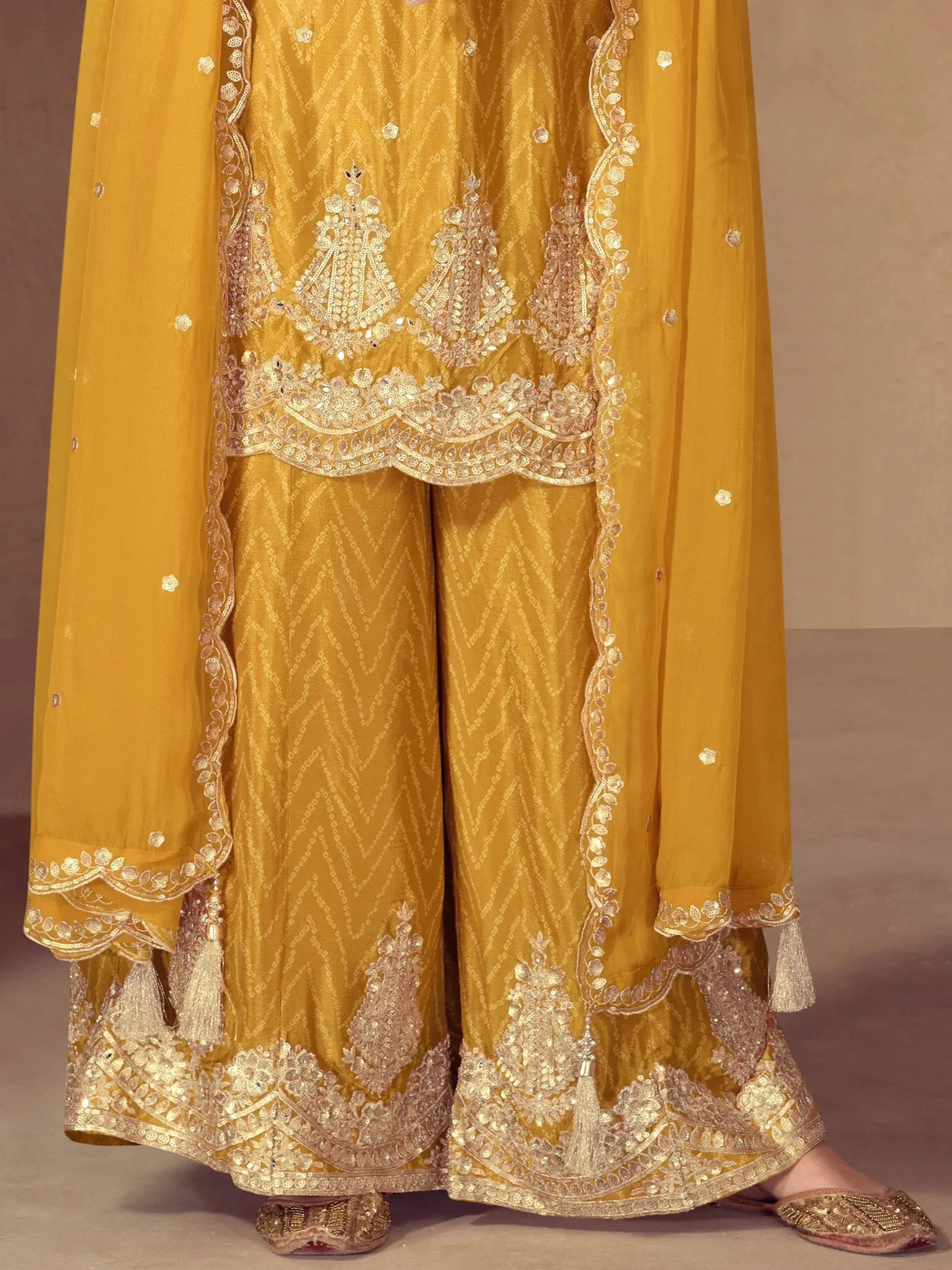 Golden ethnic sharara suit with intricate embroidery and sequin work, perfect for Indian weddings and festive occasions.