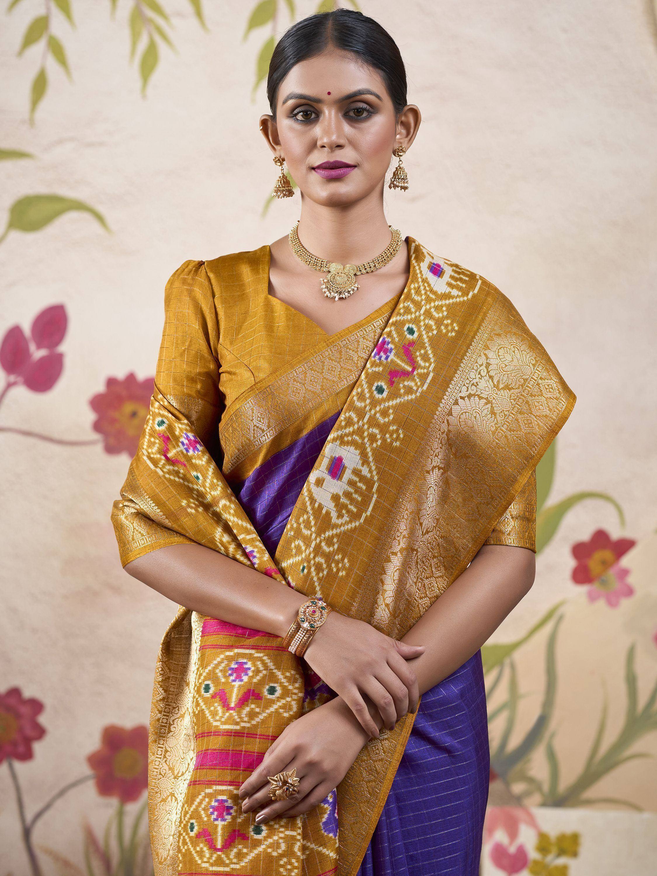 Woman in mustard yellow and purple ikat saree with gold jewelry, ethnic Indian wear