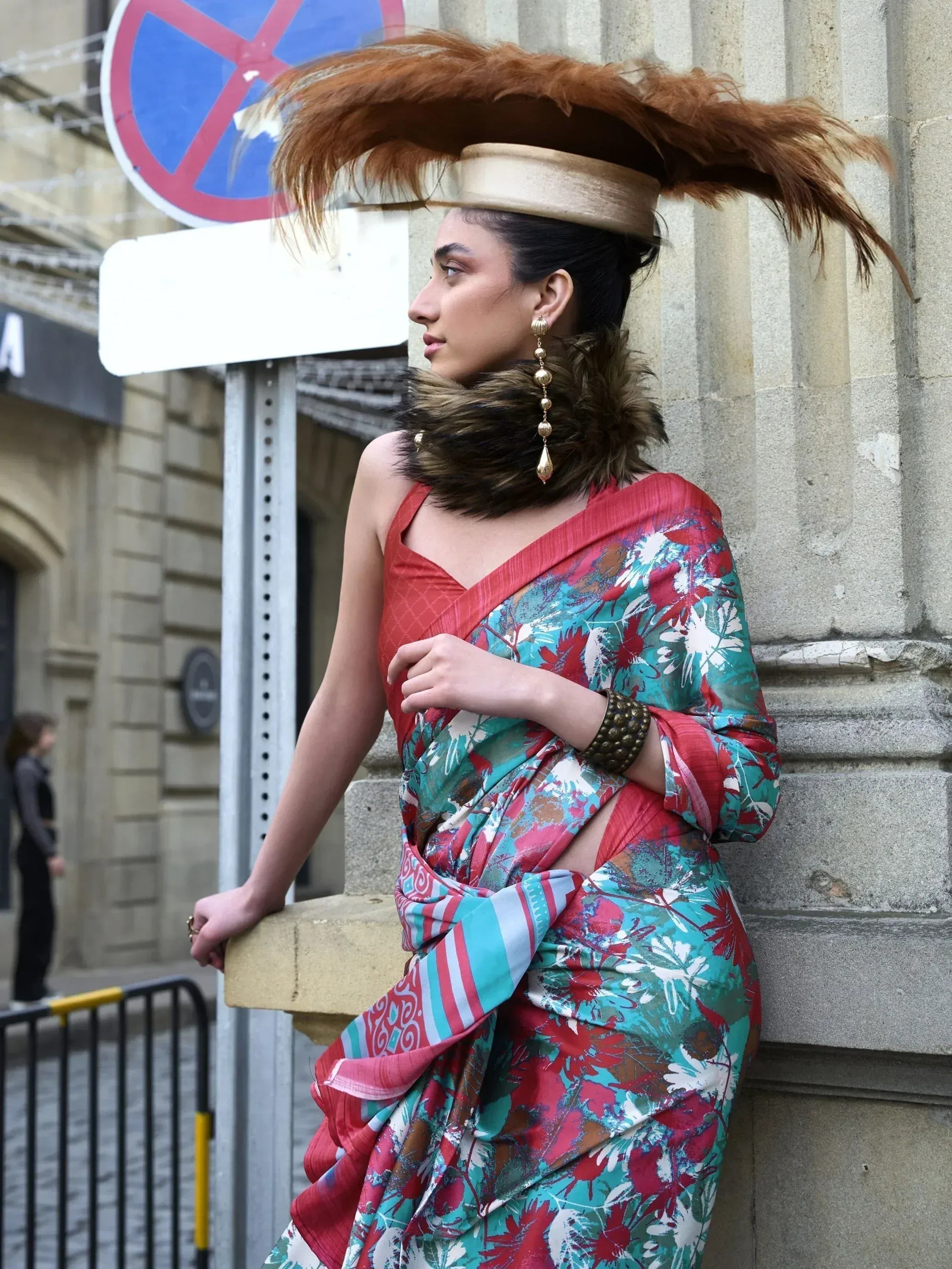 Woman in vibrant floral saree with feathered hat, stylish ethnic wear for festive occasions