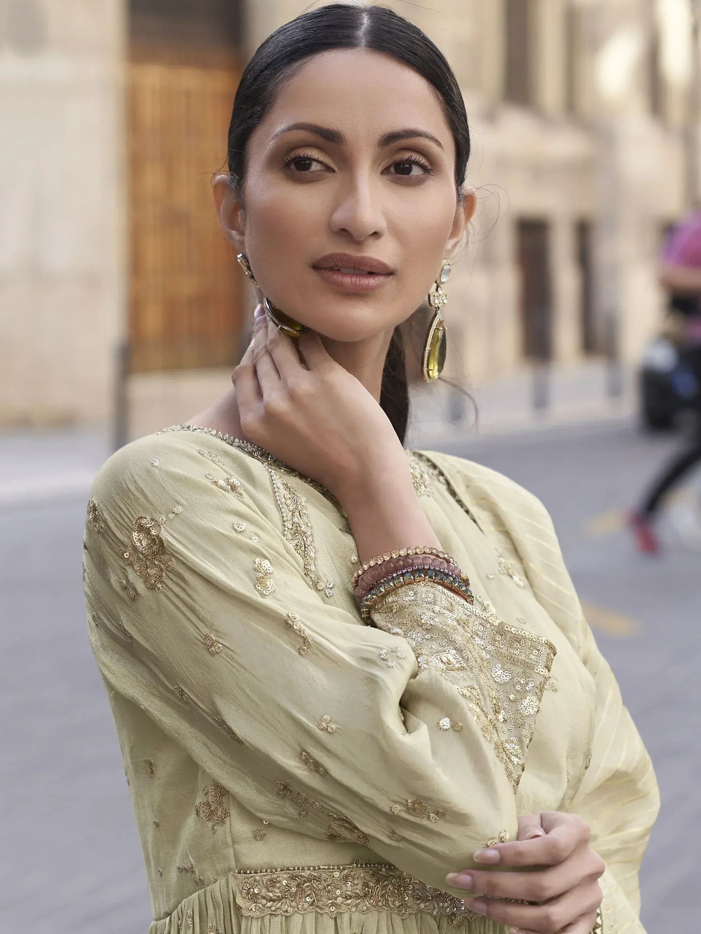 Elegant woman in gold-embroidered ethnic gown with statement earrings, perfect for Indian festive occasions.