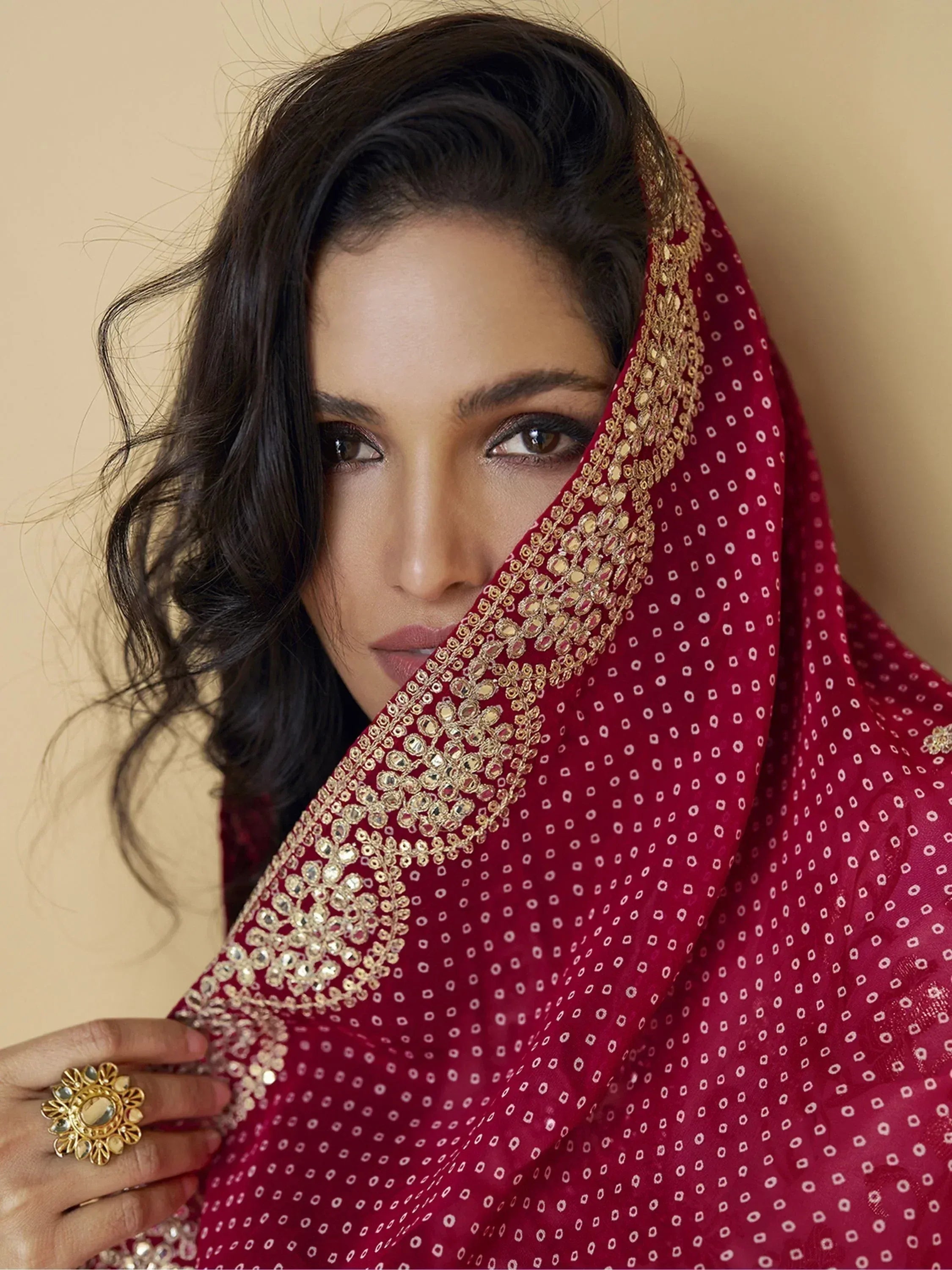 Woman in maroon ethnic saree with gold embroidery and mirror work, styled with traditional jewelry