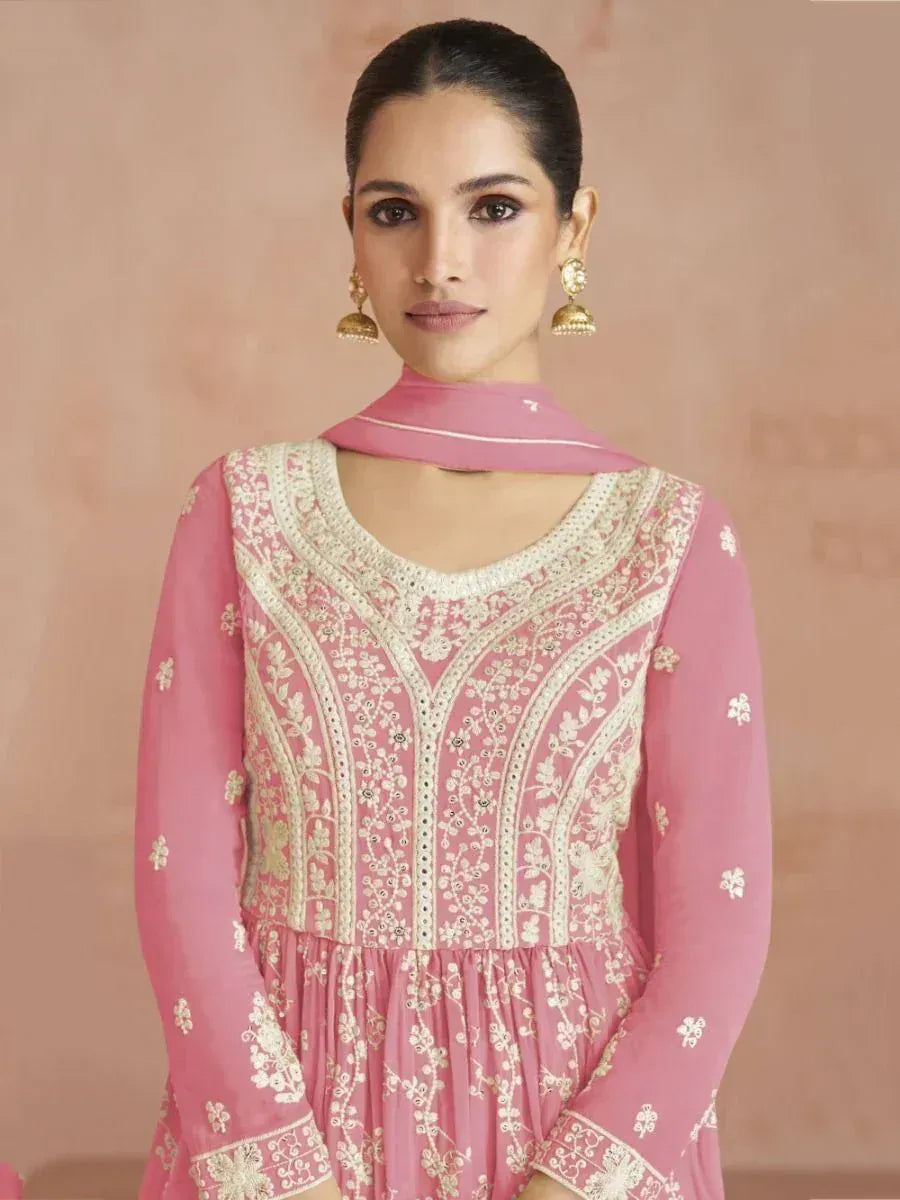 Woman wearing a pink embroidered salwar kameez with gold jhumka earrings, traditional Indian ethnic wear