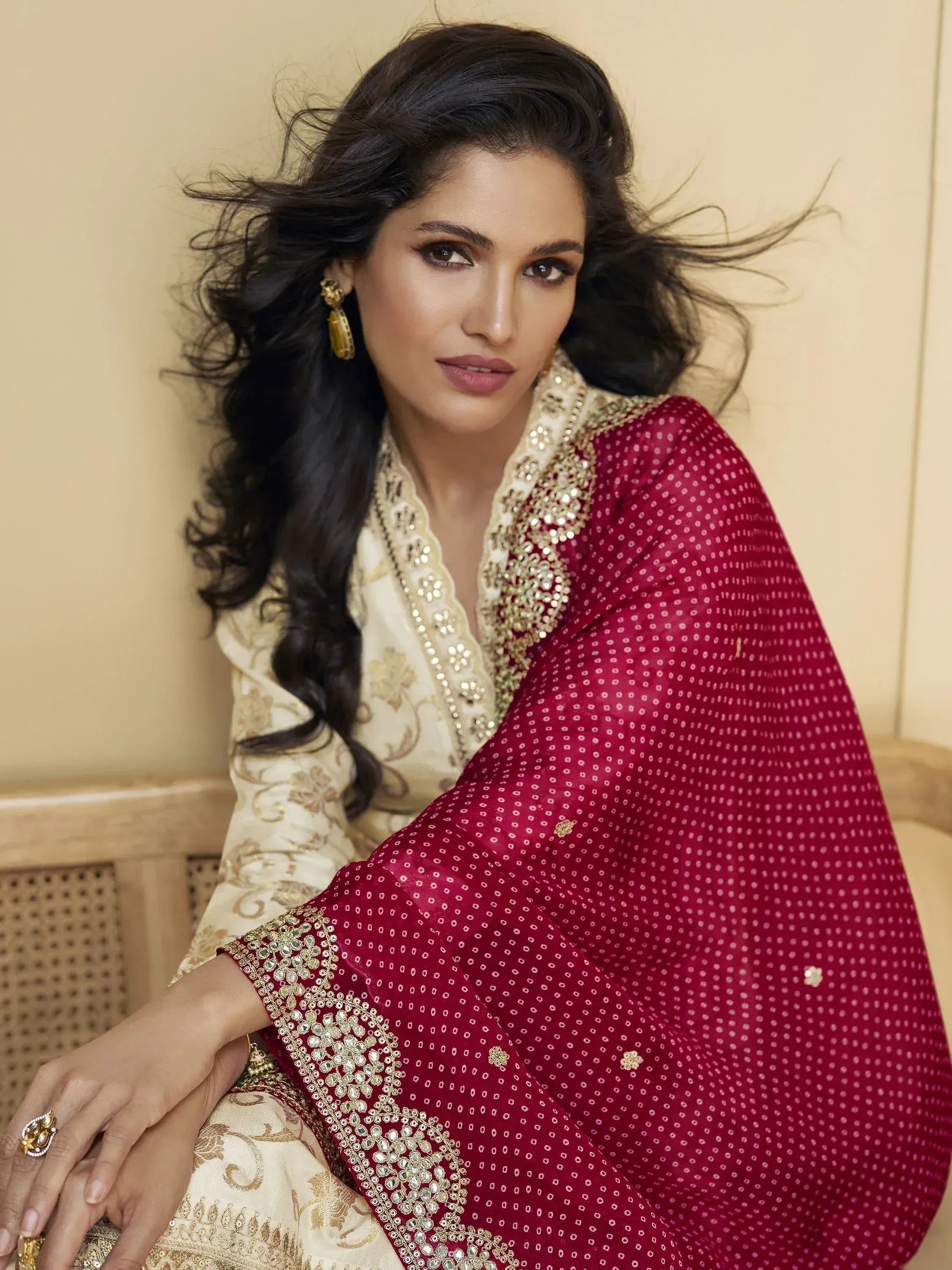 Elegant woman in cream and maroon ethnic wear with gold embroidery and sequins, styled for festive occasions