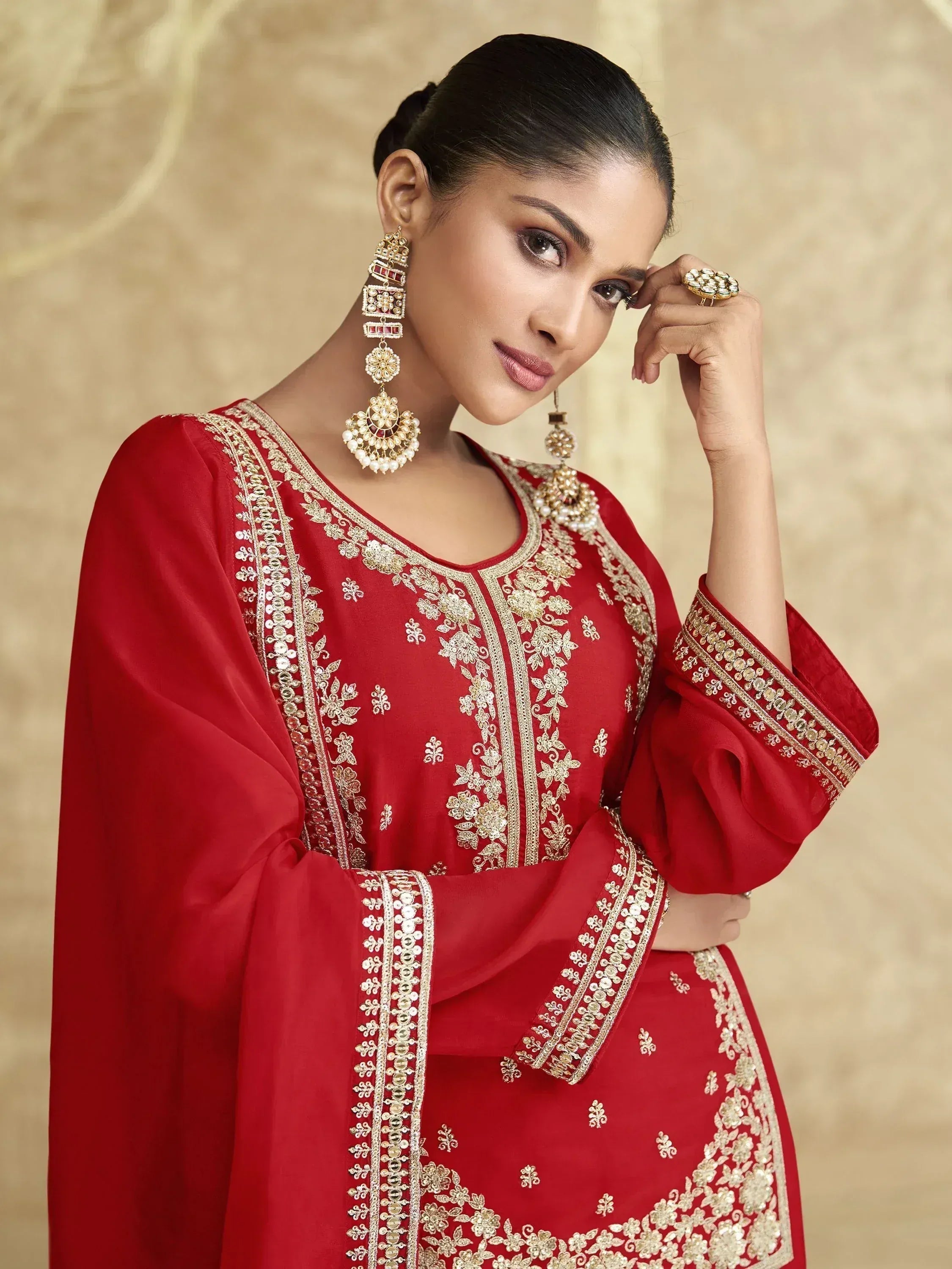 Red ethnic salwar kameez with gold embroidery and matching jewelry for festive occasions