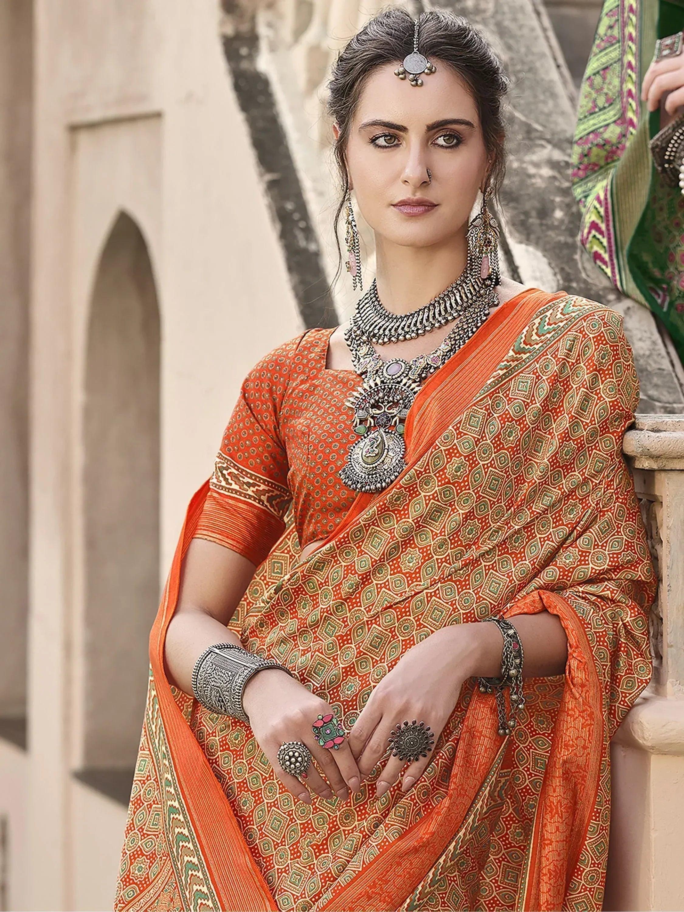 Woman in orange printed saree with traditional jewelry, ethnic Indian wear