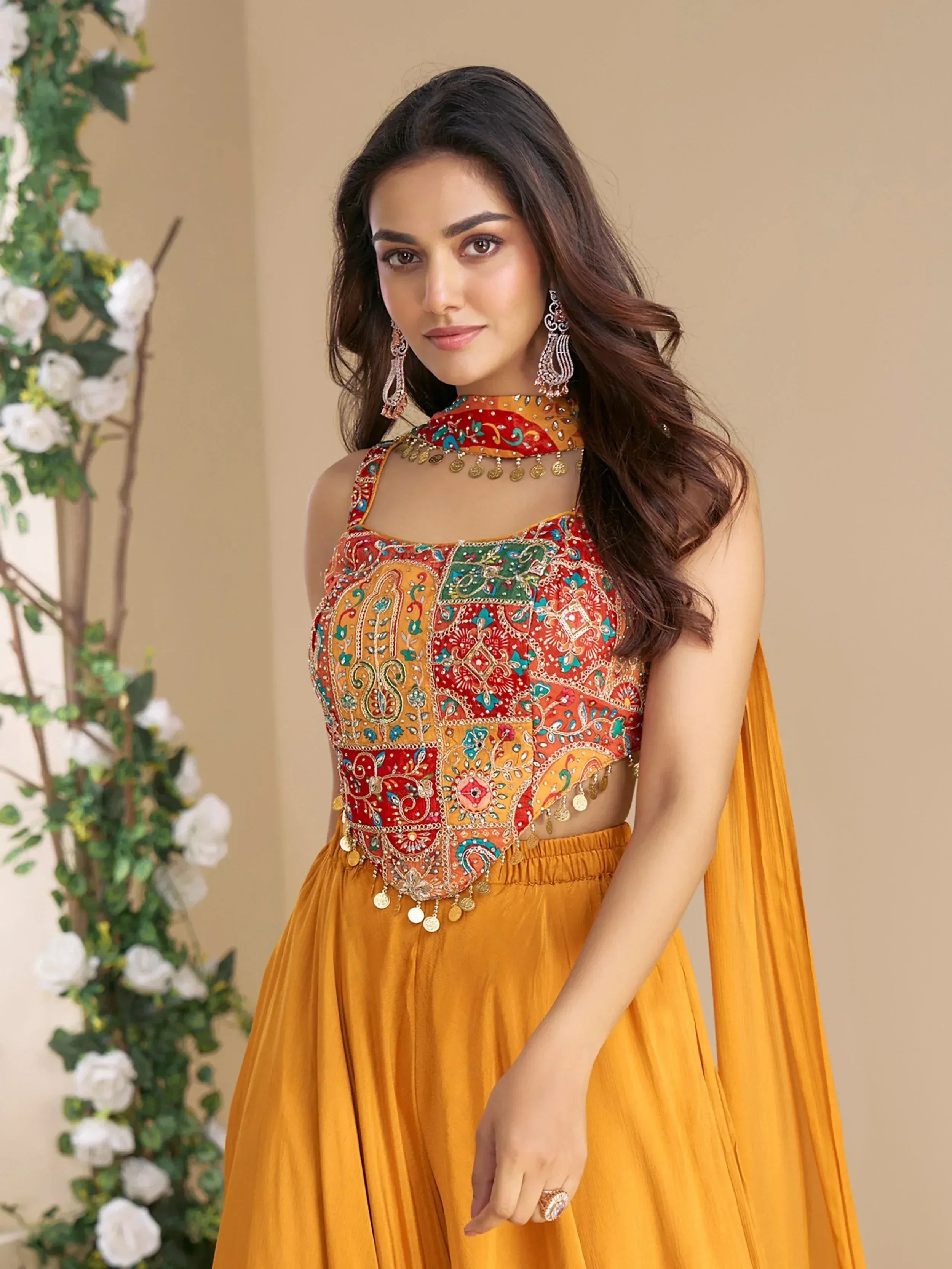 Woman in vibrant Indian ethnic wear with embroidered halter top and mustard skirt, perfect for festive occasions.