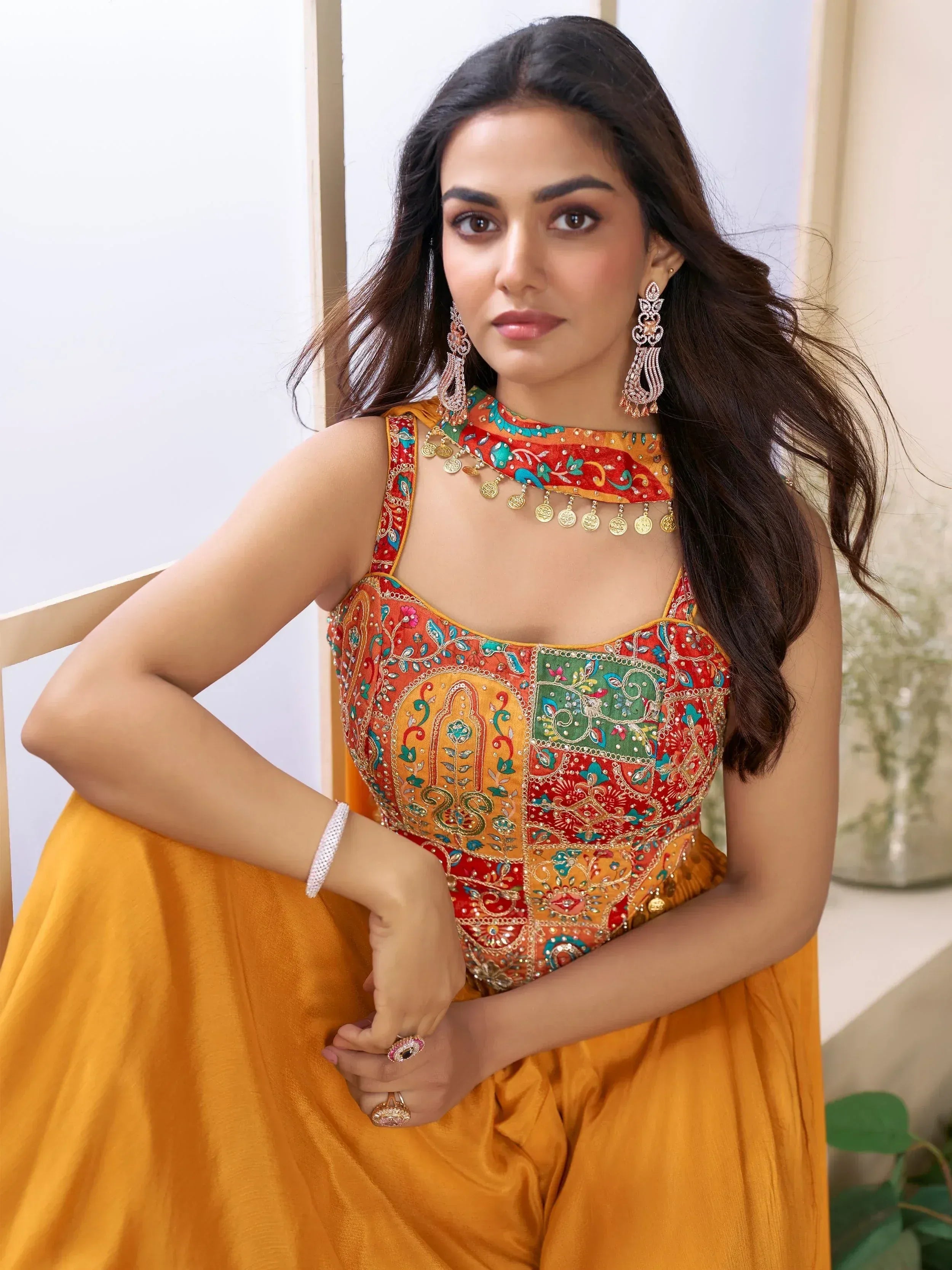 Woman in vibrant Indian ethnic gown with embroidered blouse and gold coin necklace, perfect for festive occasions.