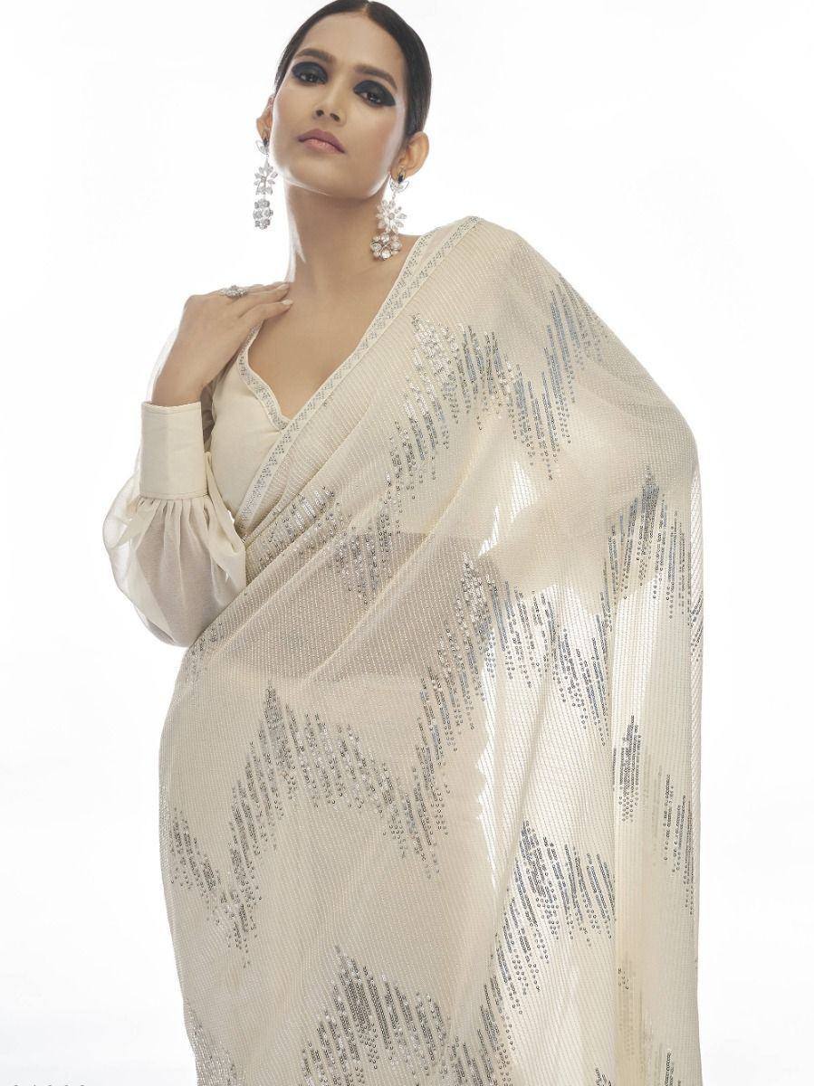Elegant cream saree with silver sequin work, styled with puff sleeves and statement earrings for festive occasions.