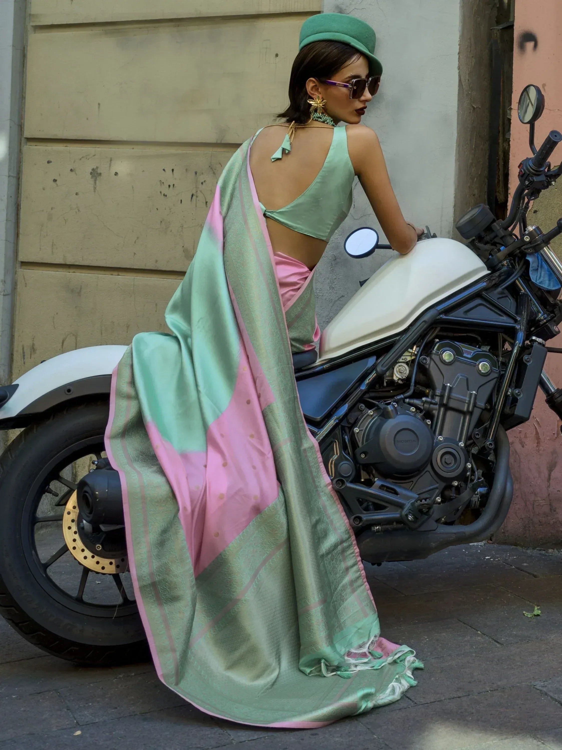 Woman in mint green and pink saree with backless blouse, posing on motorcycle, ethnic fashion