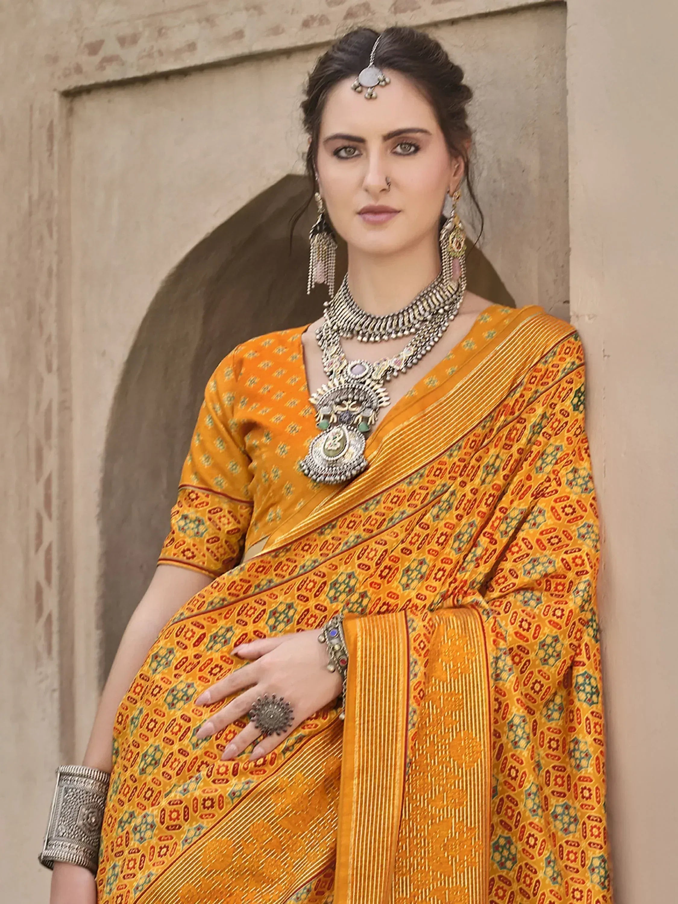 Woman in vibrant yellow printed saree with traditional Indian jewelry, perfect for ethnic occasions