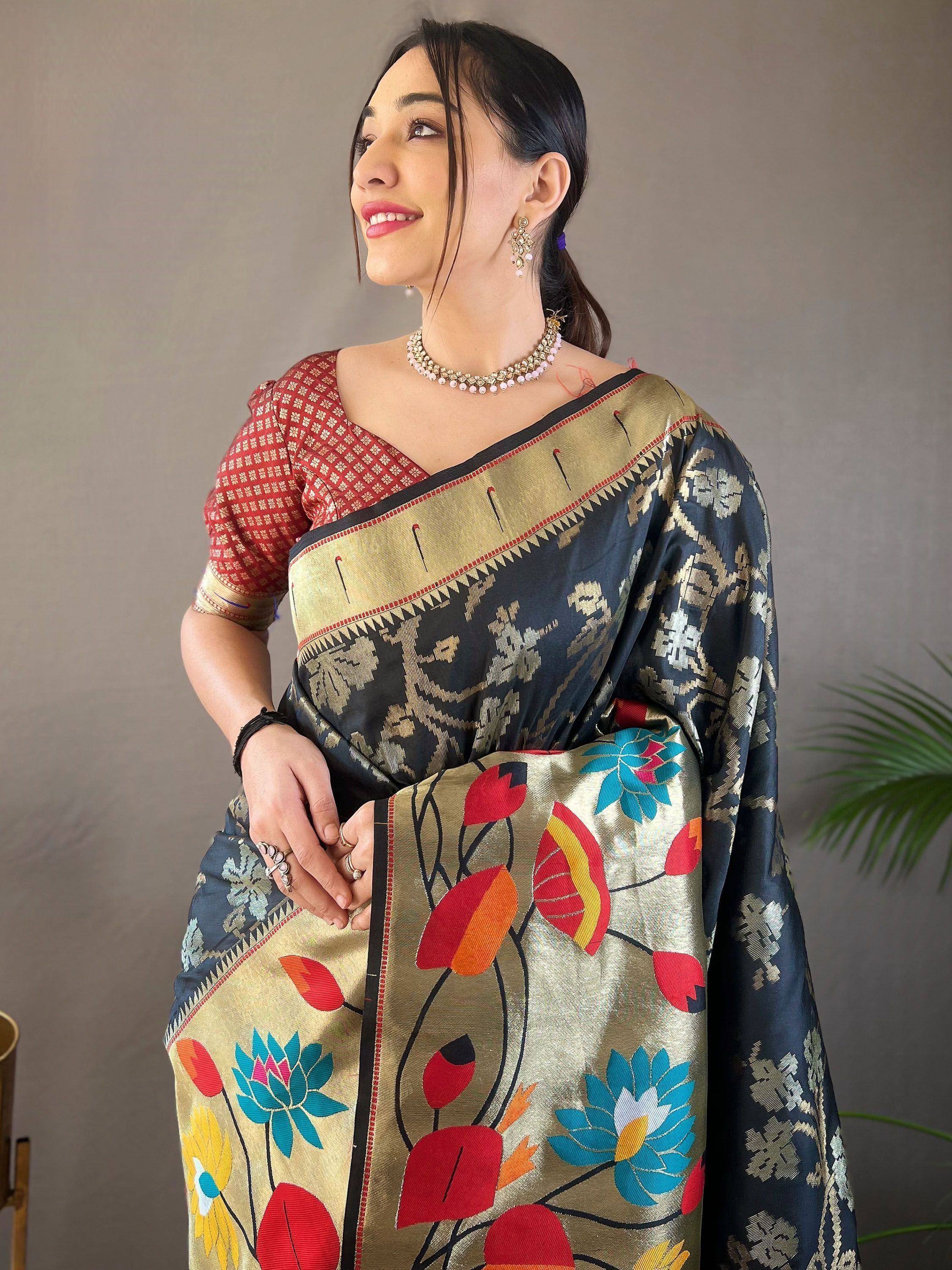 Woman in elegant black and gold saree with colorful floral pallu, paired with red patterned blouse, perfect for Indian ethnic occasions.