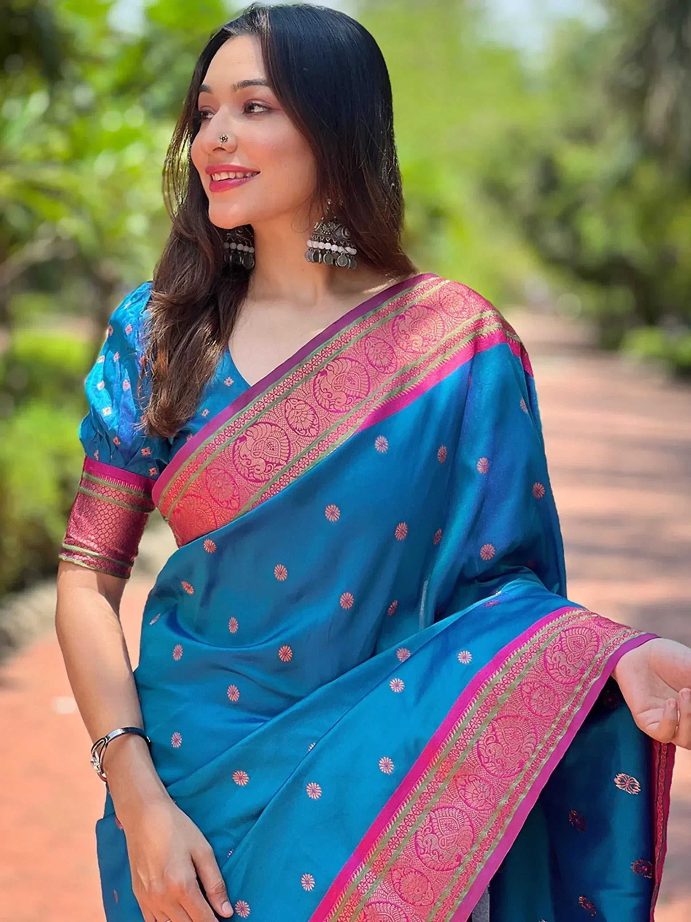 Blue Indian saree with pink border and floral motifs, styled with traditional earrings for ethnic wear
