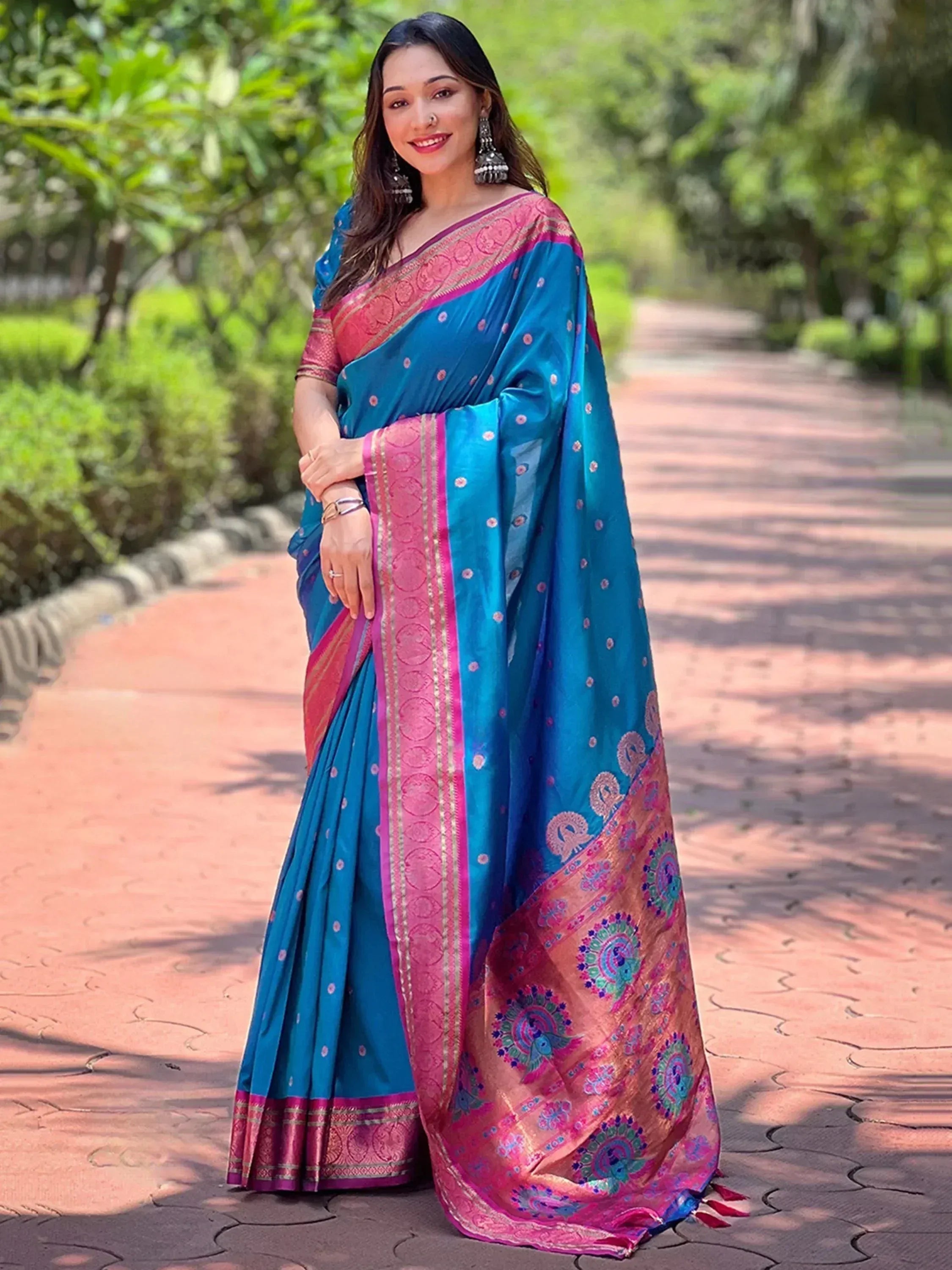 Woman in vibrant blue and pink designer saree with peacock motifs, perfect for ethnic occasions