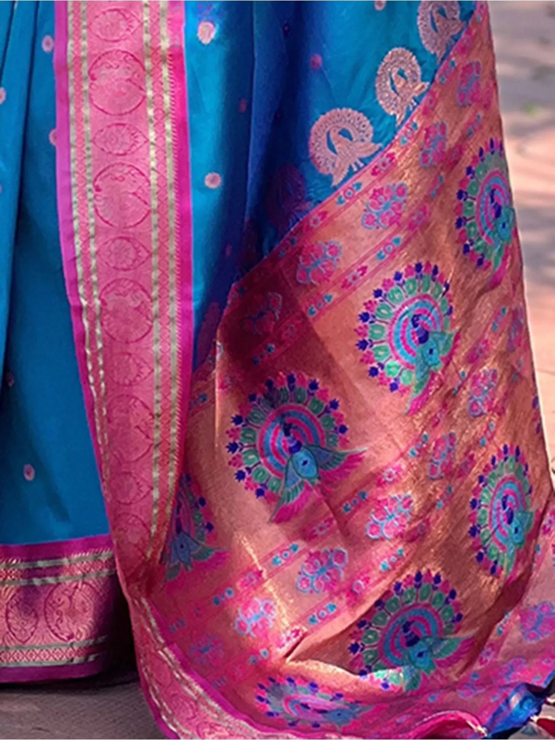 Vibrant blue and pink Indian saree with peacock motifs and gold border, perfect for ethnic occasions.