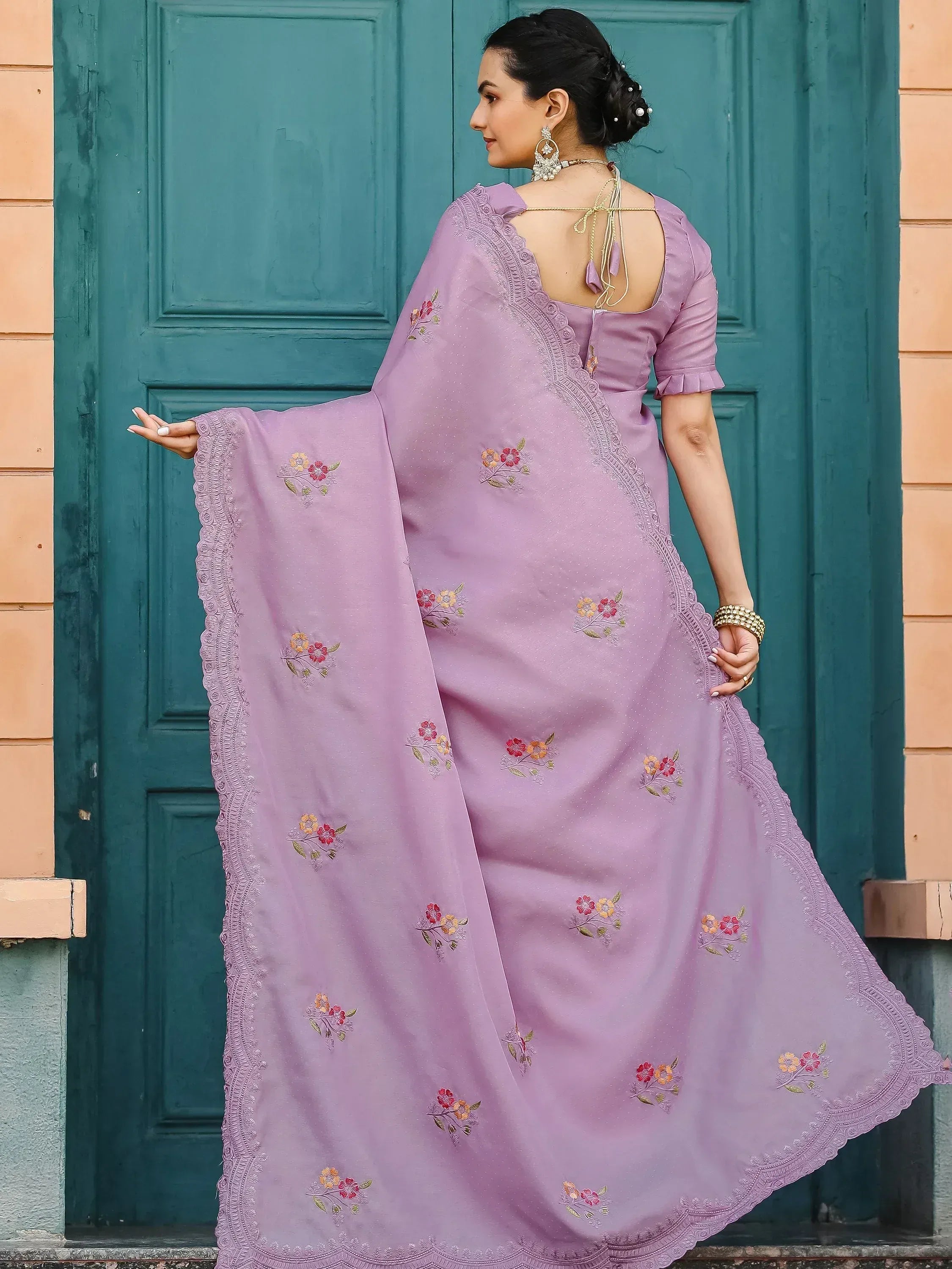 Lavender floral embroidered saree with scalloped border, back view against teal door