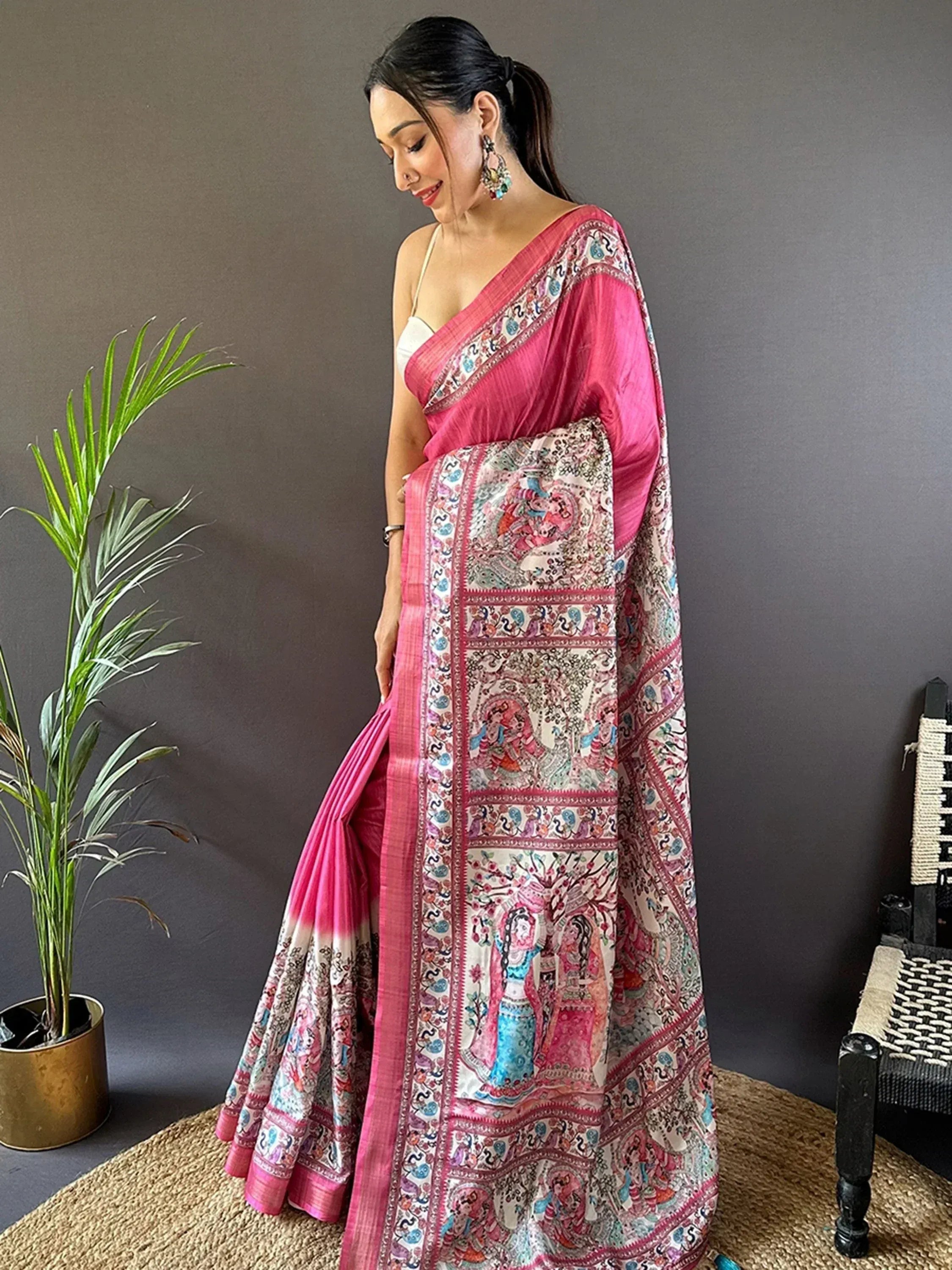 Woman in pink printed saree with traditional Indian motifs, styled with statement earrings and white blouse.