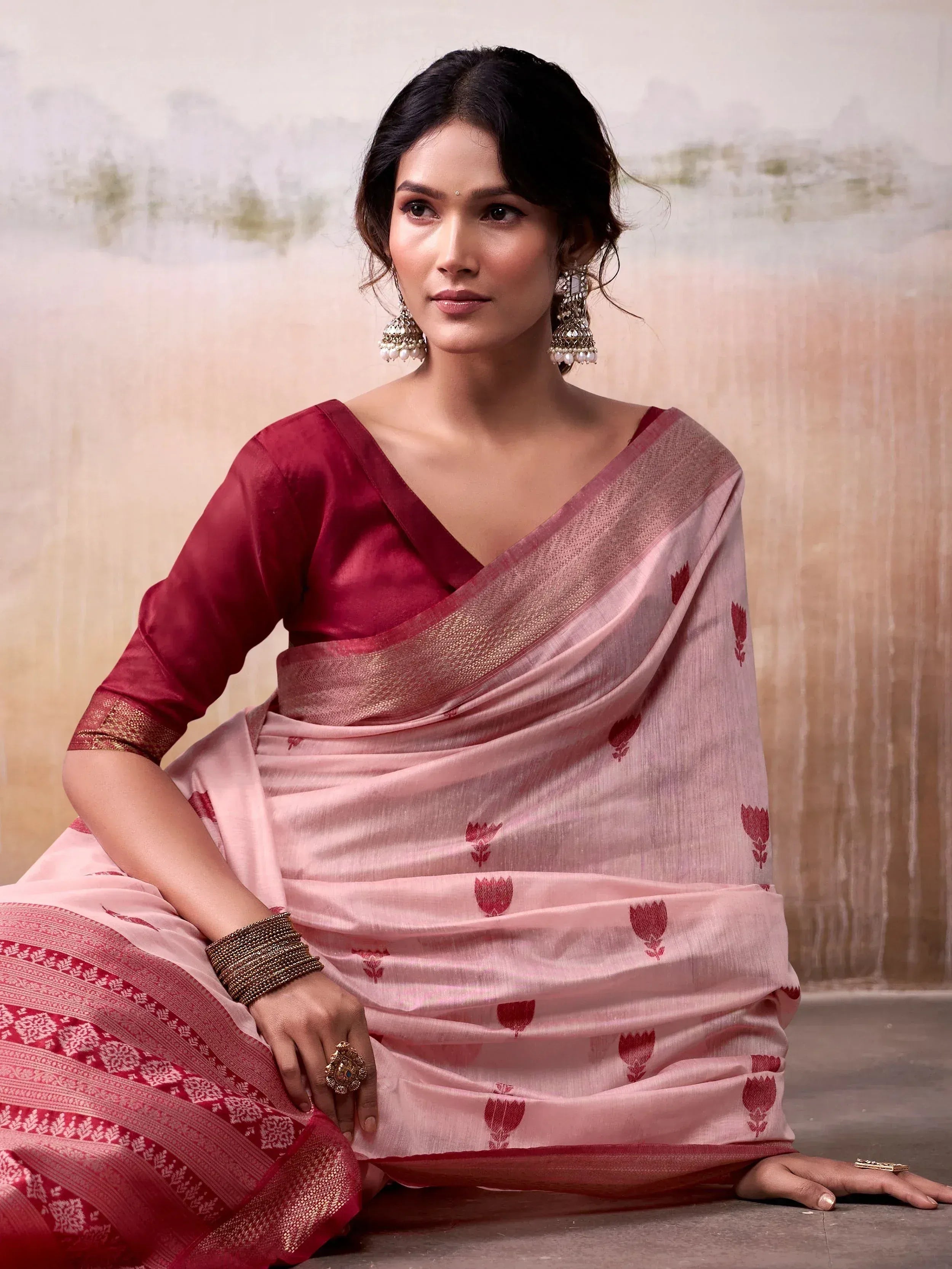 Pink and maroon floral saree with gold border, styled with traditional Indian jewelry for ethnic wear