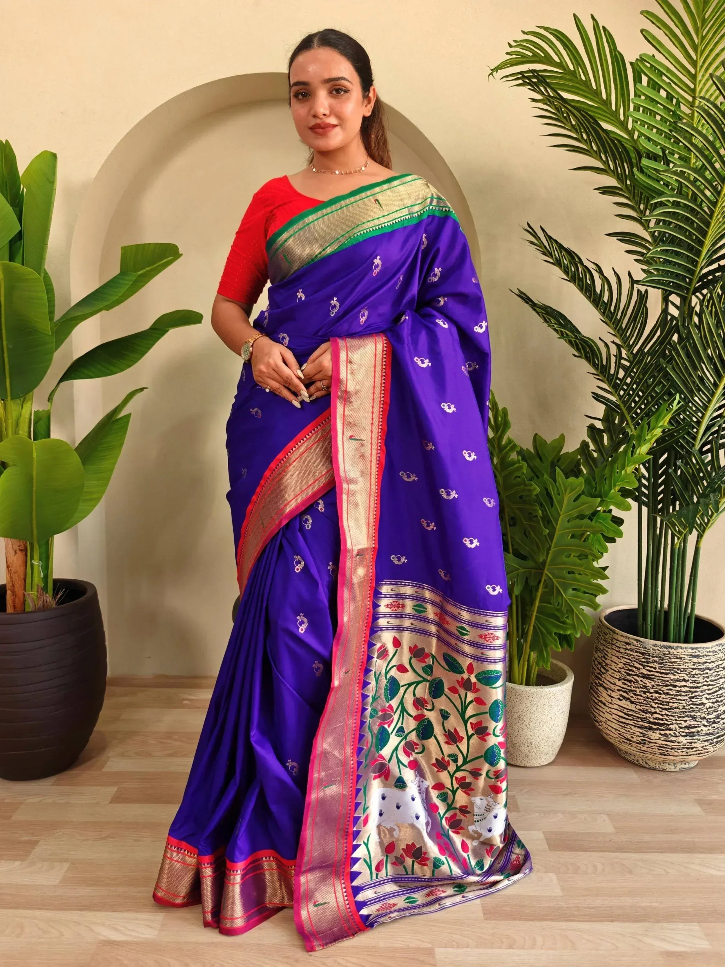 Woman in vibrant purple silk saree with floral border and red blouse, styled for ethnic occasions
