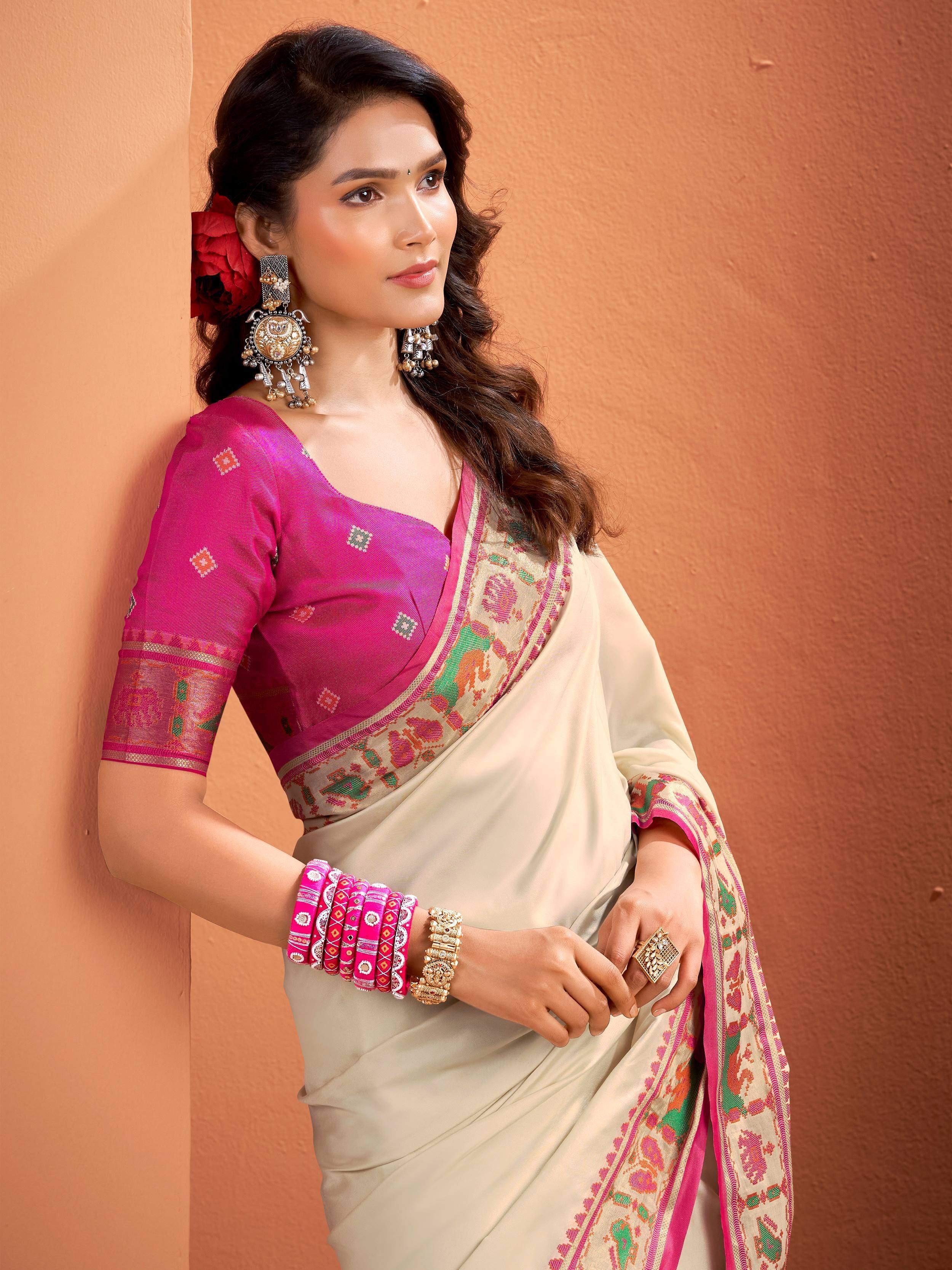 Woman in cream saree with pink embroidered border and matching blouse, styled with traditional jewelry