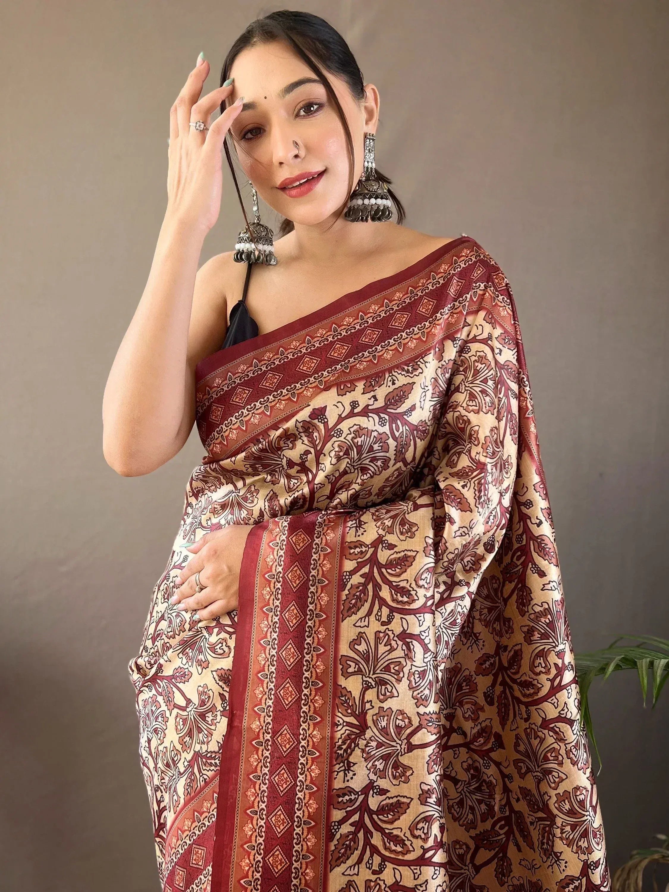 Woman in elegant maroon and beige floral print saree with traditional jewelry, showcasing Indian ethnic wear.
