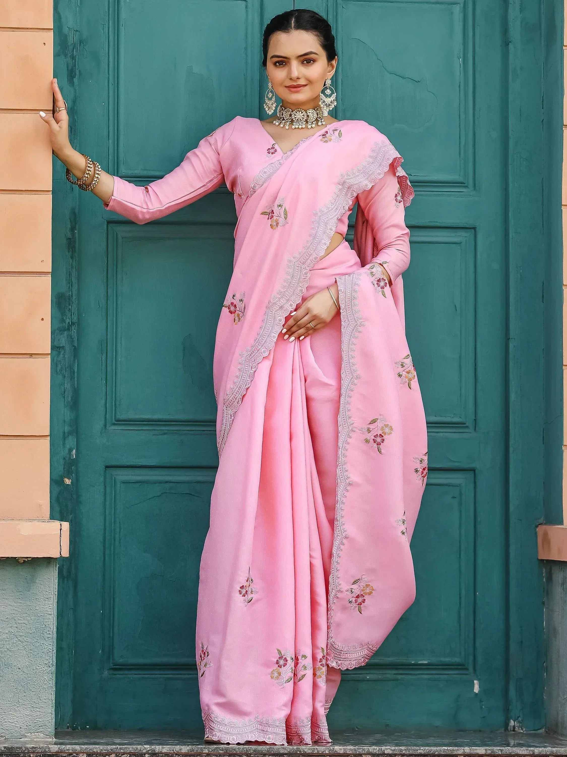 Pink embroidered saree with floral details and lace border, styled with traditional jewelry